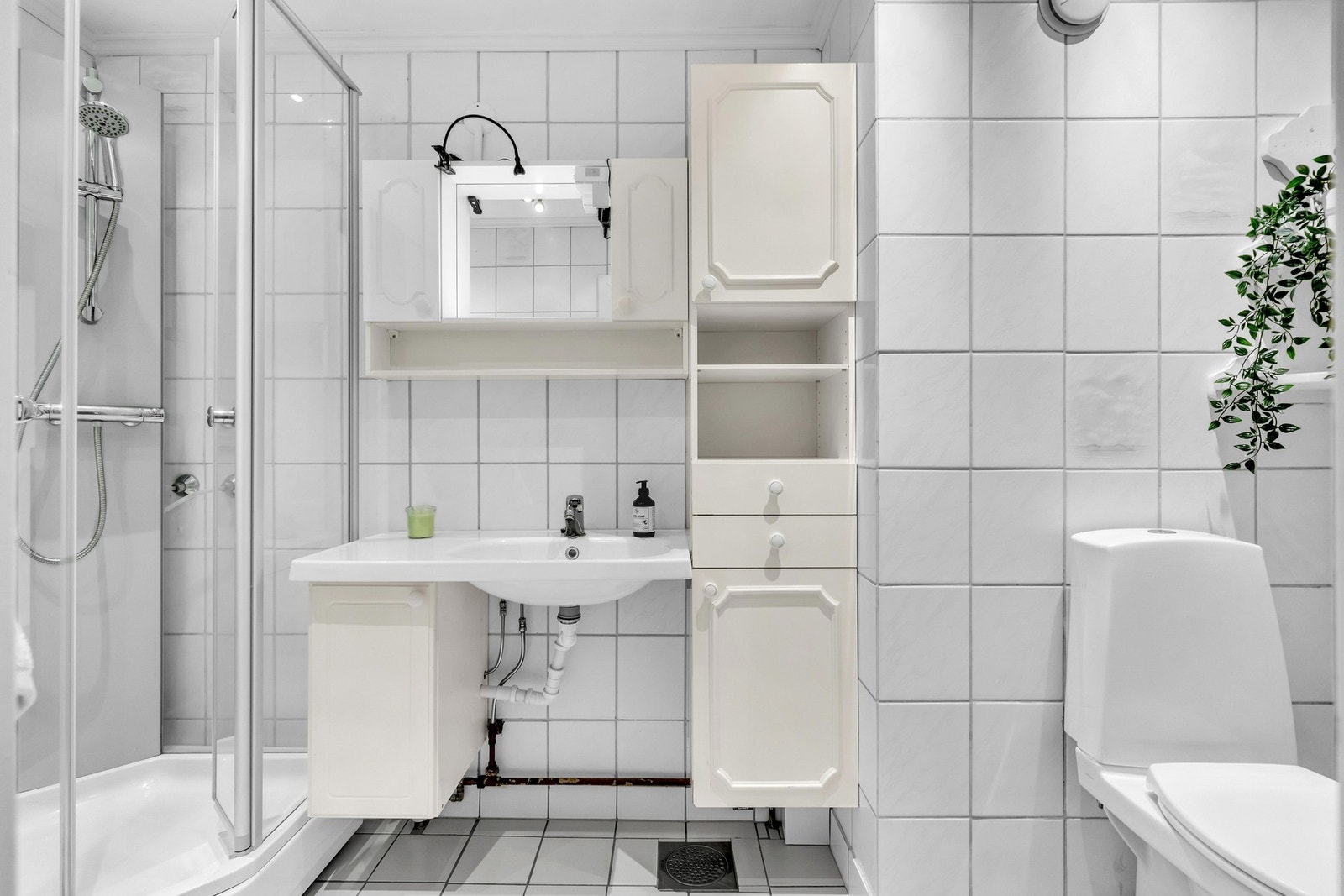 Baderomsinnredningen er bestående av vegghengt servantskap, skap på vegg, speil, gulvstående toalett og dusjkabinett. Galleribilde