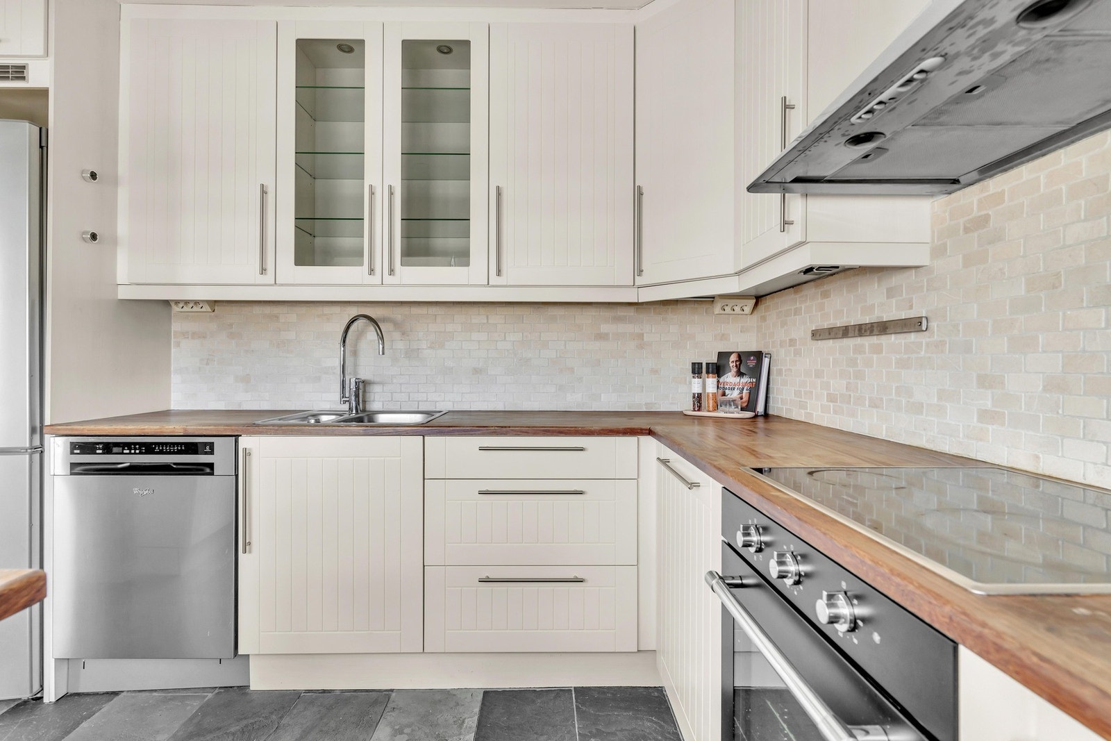 Lys kjøkkeninnredning med profilerte fronter og benkeplate av heltre med nedfelt oppvaskkum av rustfritt stål. Galleribilde