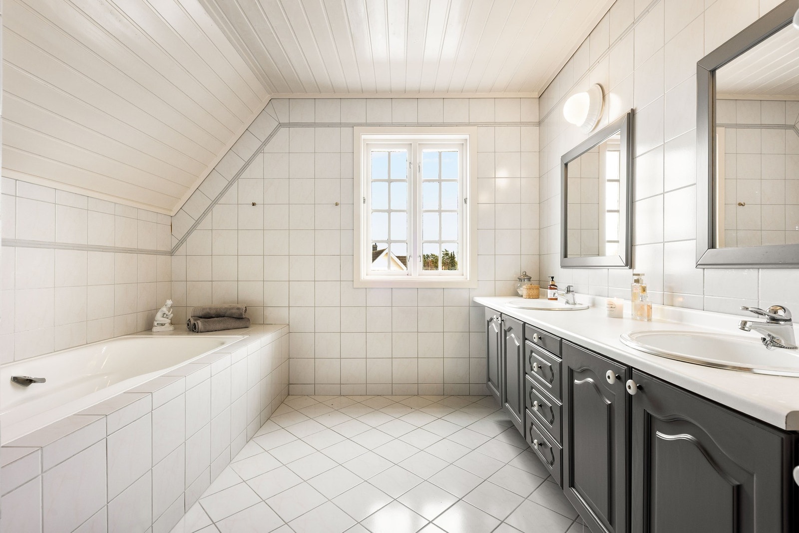 Flislagt bad med badekar og stor innredning. Galleribilde