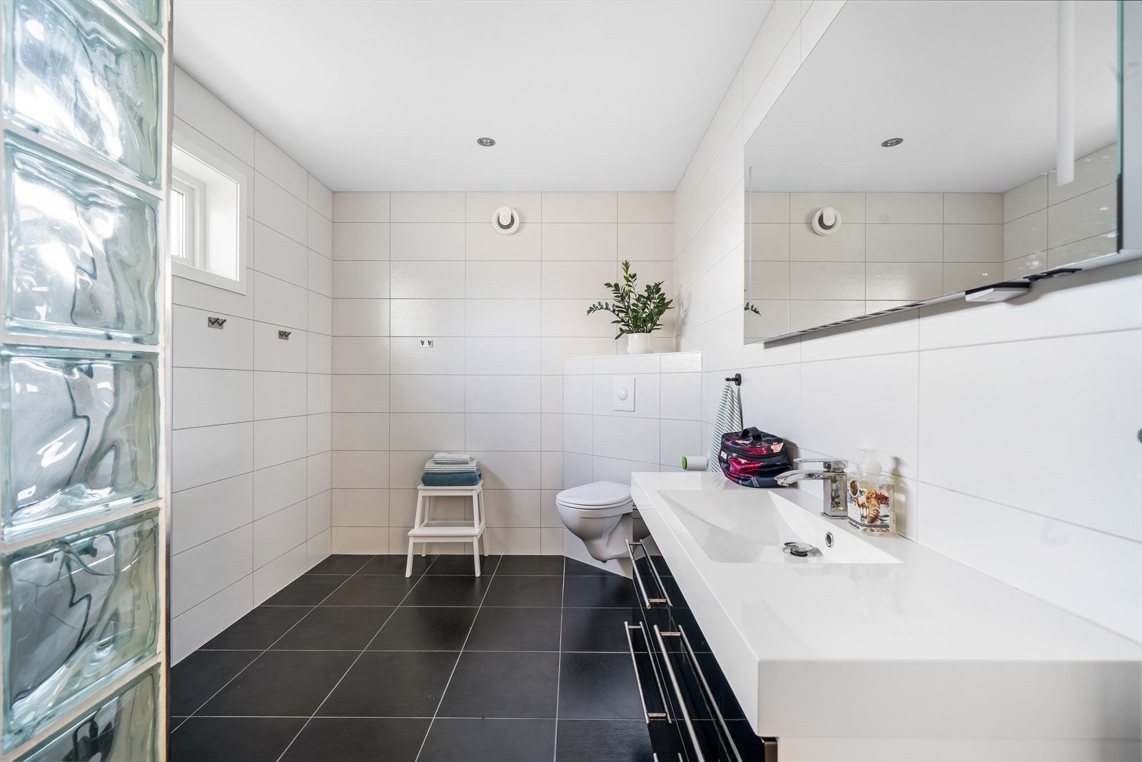 Fliselagt bad med varmekabler i gulv. Badet er innredet med baderomsinnredning, toalett og dusjnisje med glassvegg. Galleribilde