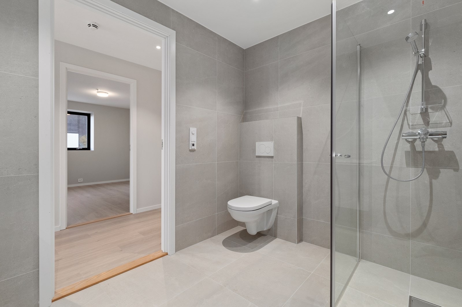 Helfliset bad med 60*60 flis, vegghengt toalett, stor dusjnisje og praktisk baderomsinnredning. Galleribilde