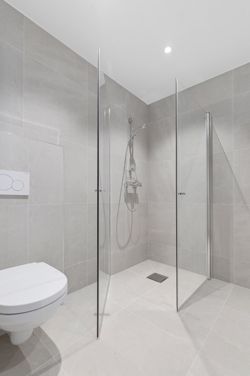 Helfliset bad med 60*60 flis, vegghengt toalett, stor dusjnisje og praktisk baderomsinnredning. Galleribilde