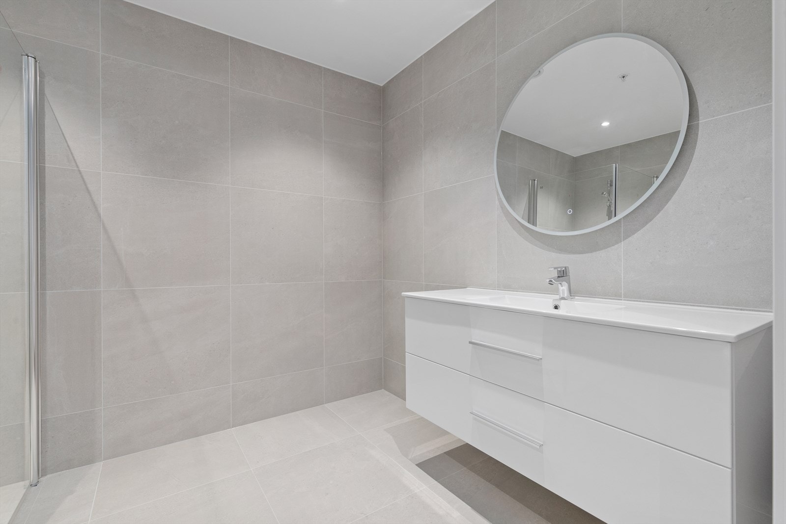 Helfliset bad med 60*60 flis, vegghengt toalett, stor dusjnisje og praktisk baderomsinnredning. Galleribilde