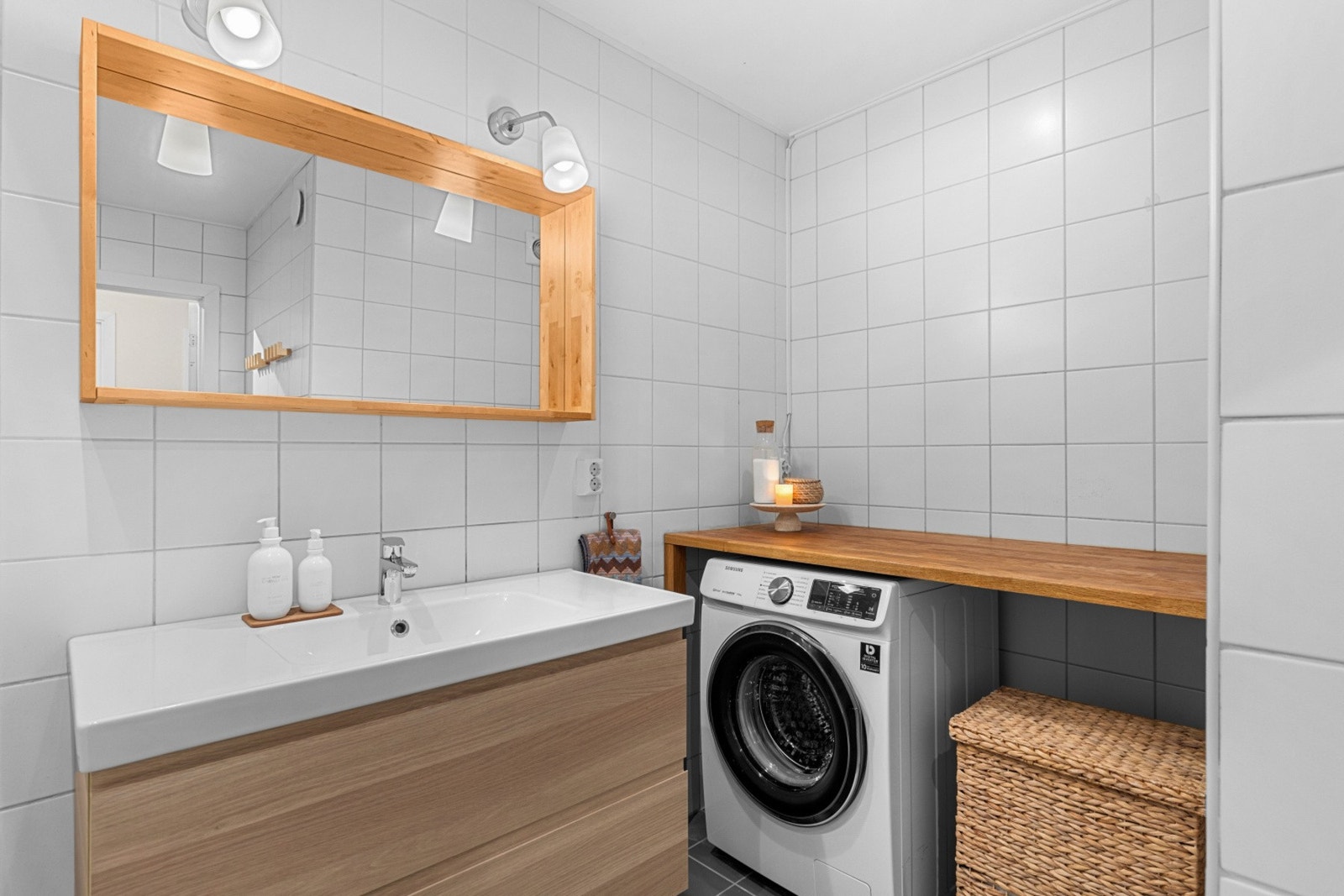 Badet er moderne innredet med baderomsinnredning under servant, opplegg for vaskemaskin under benkeplate og badekar. Galleribilde