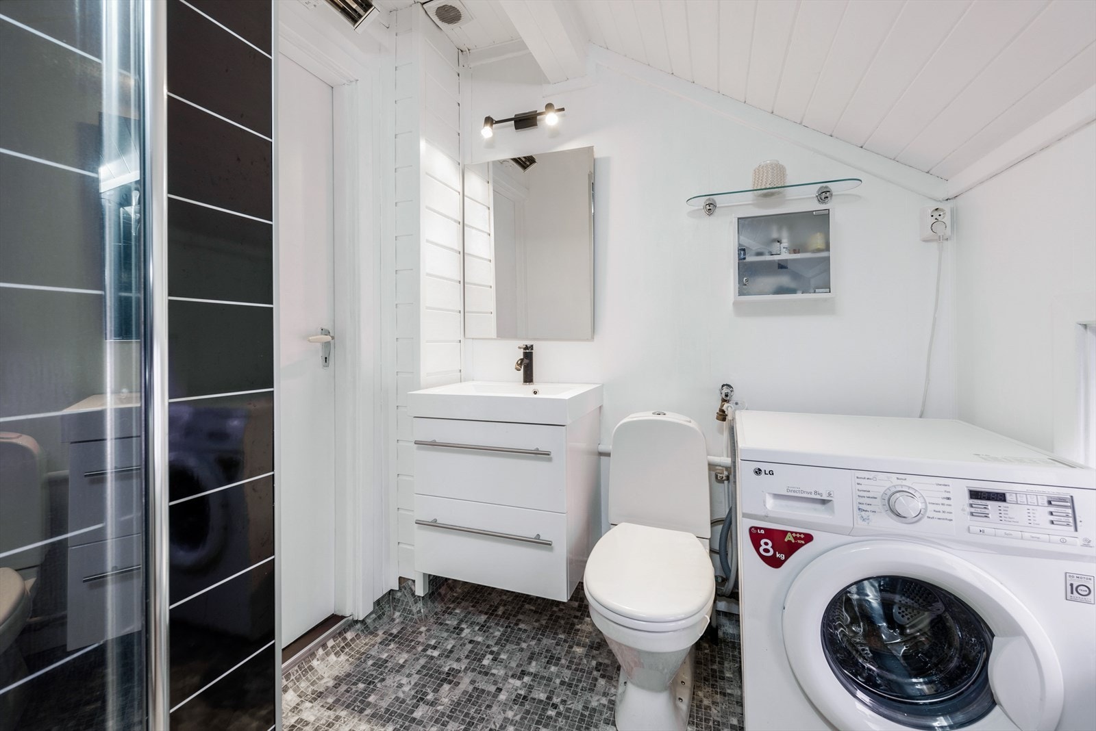 Lyst baderom med våtromsbelegg på gulv, overflater med våtromsplater, malt panel og malte plater, samt elektrisk styrt vifte. Galleribilde