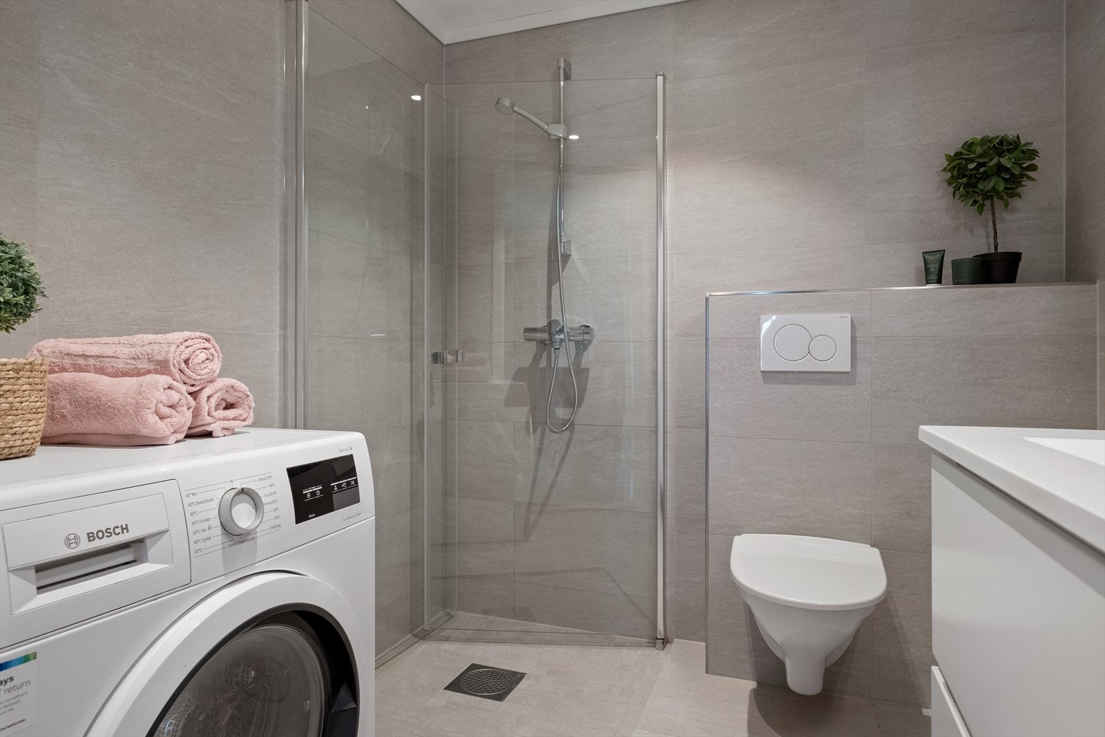 Badet er utstyrt med vegghengt wc, dusjdører, innredning med servant og opplegg for vaskemaskin. Galleribilde