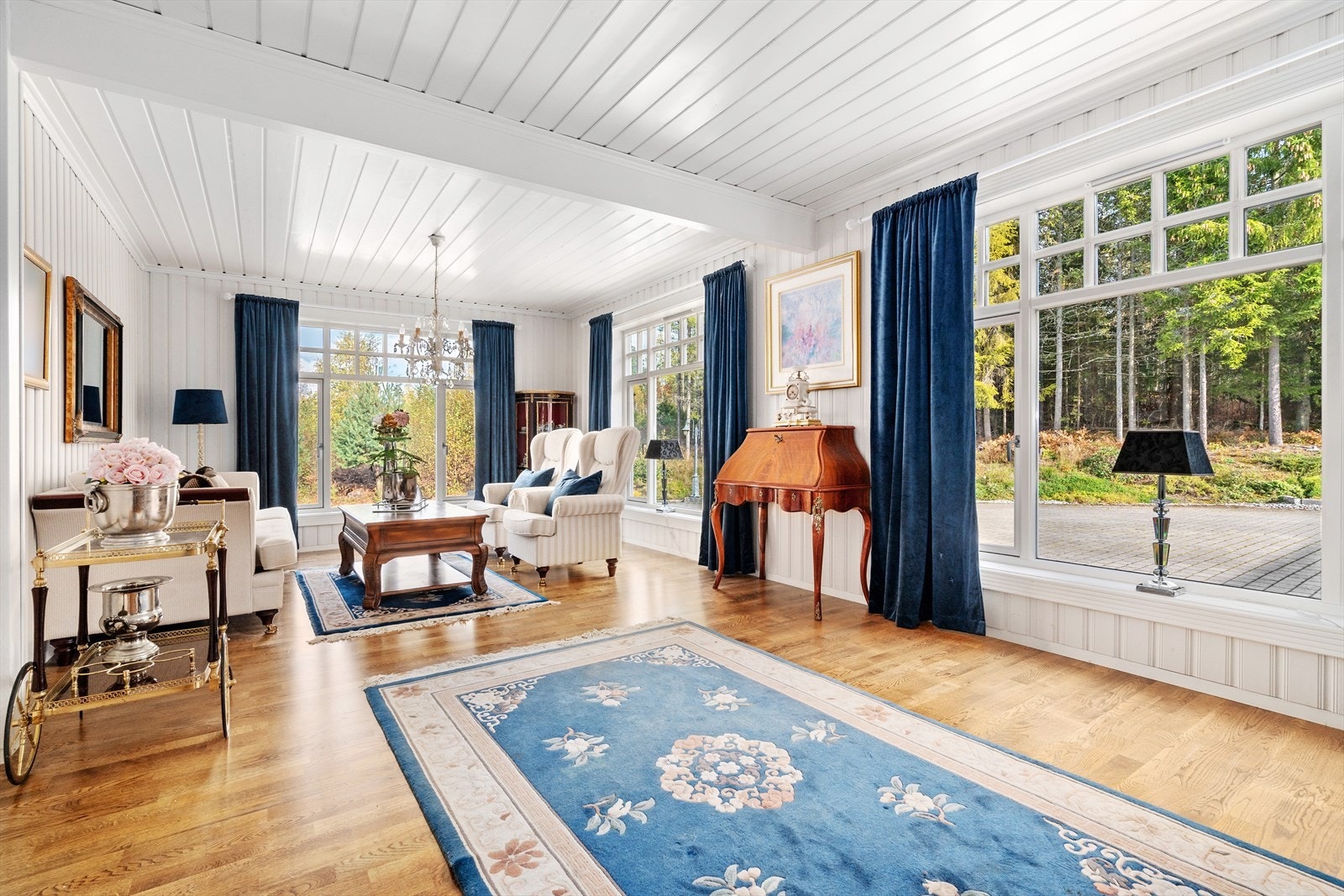 Fra spisestuen kommer en videre inn til dagligstuen. Stuen er pent innredet med parkett på gulv og trepanel på vegg malt i en lys fargetone. Galleribilde