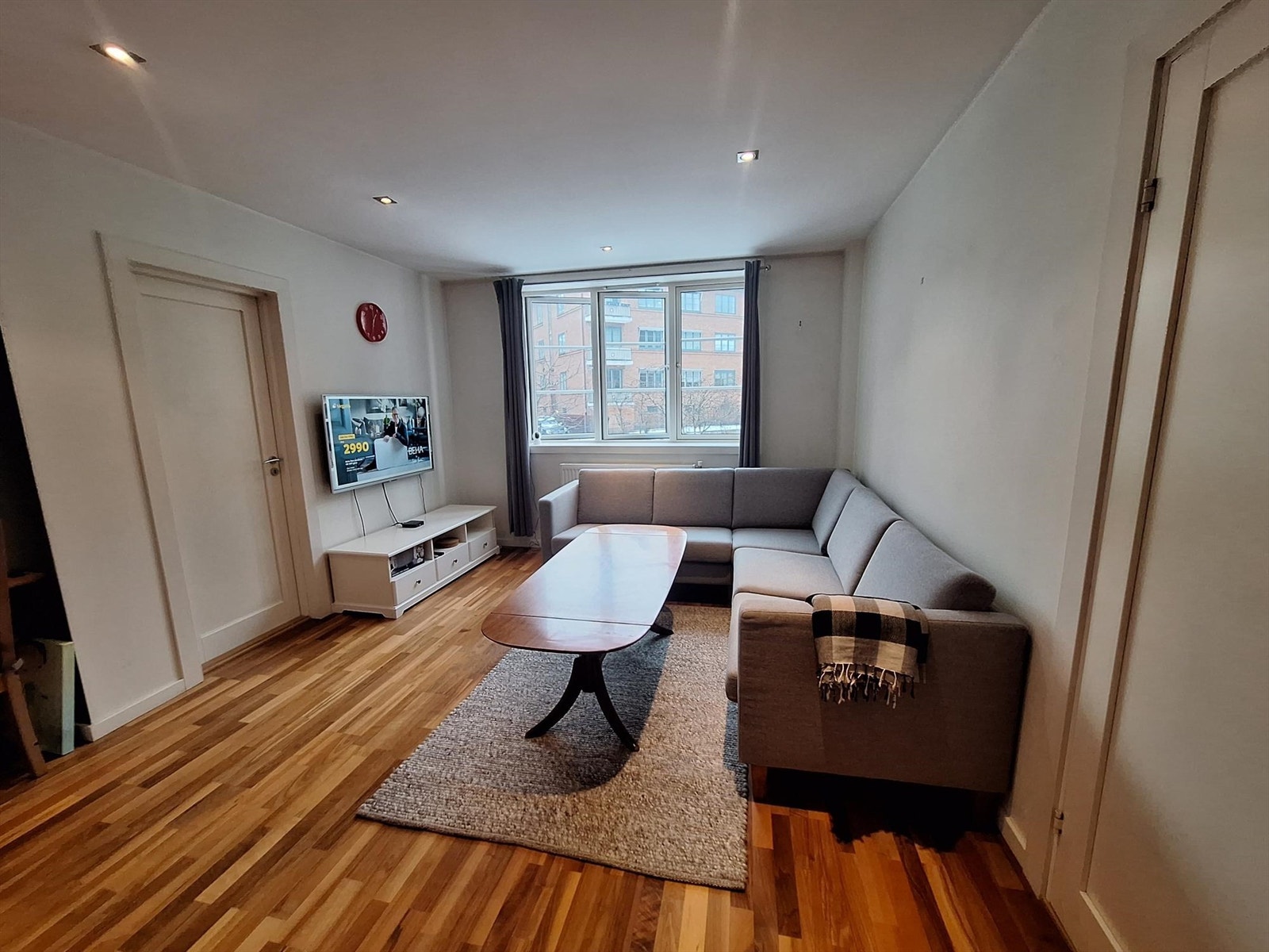 Stuen er innredet med sofagruppe med bord og tv bord med åpen løsning mot kjøkken Galleribilde