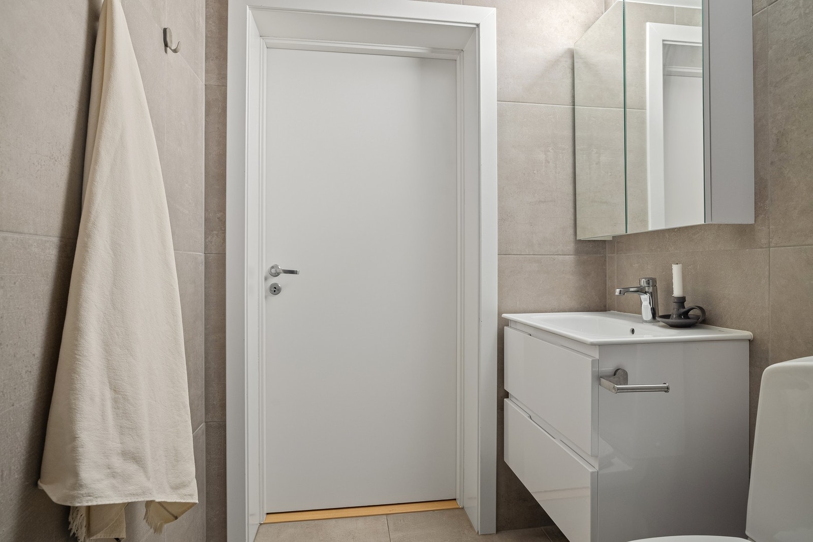 Badet inneholder servant med innredning, speilskap, dusjhjørne med innfellbare glassdører og toalett. Galleribilde