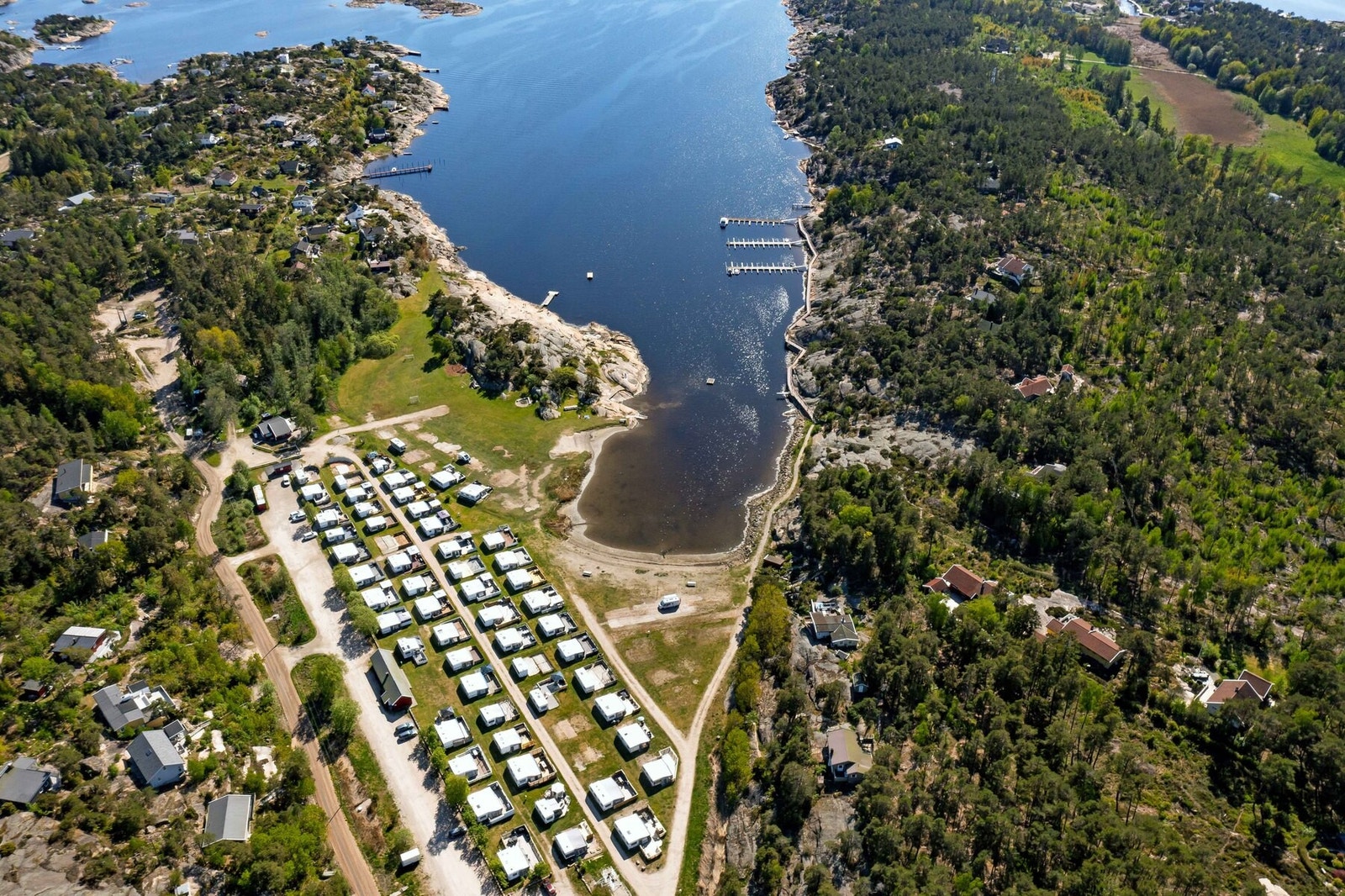 Dronefoto over tomteområdet og Enhuskilen camping. Her finner du en flott langgrunn sandstrand Galleribilde