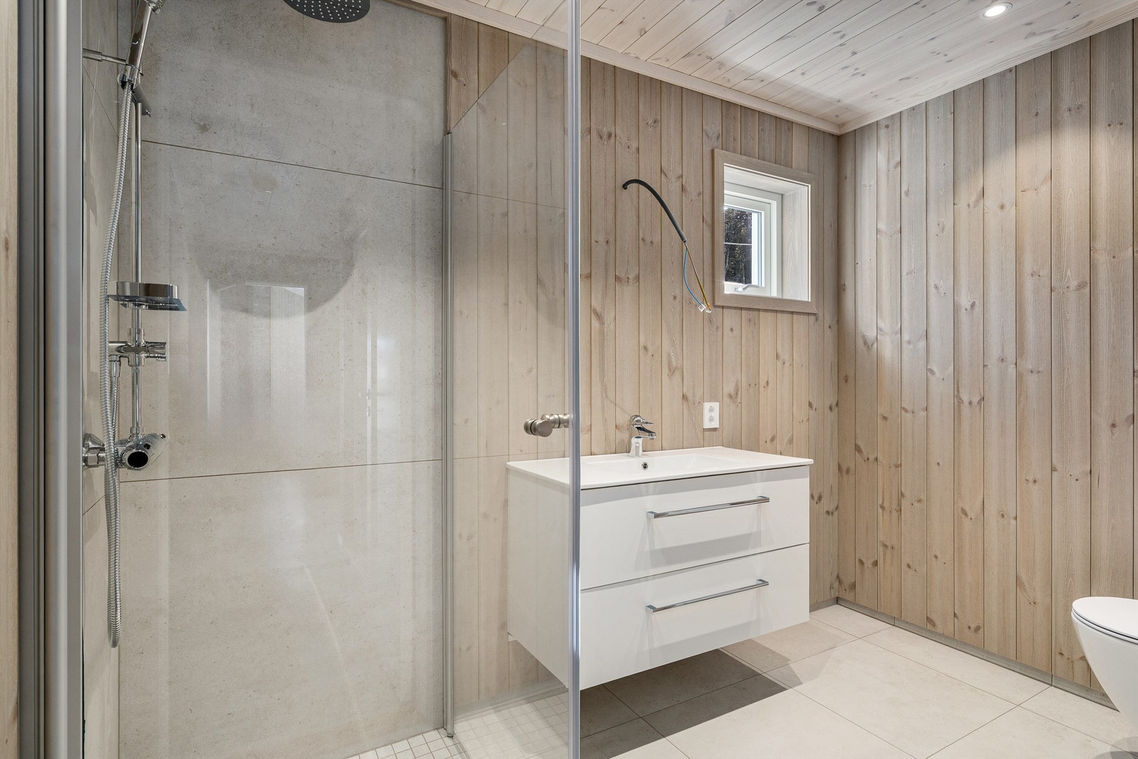 Badet er enkelt og tidløst, flisene med gråsjattering står fint til den enkel baderomsinnredningen. Speil med belysning vil bli montert før visning. Galleribilde