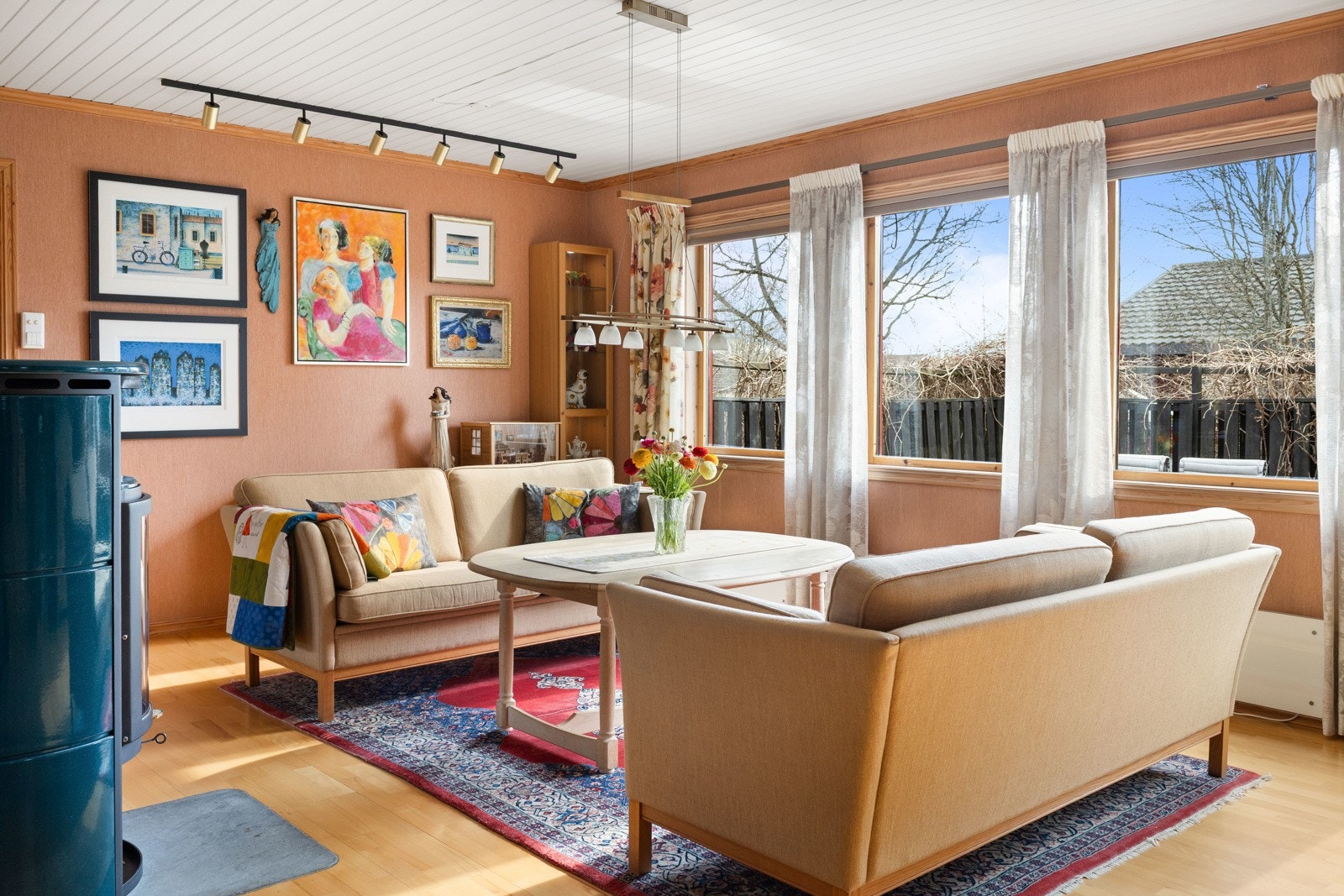 Romslig stue med store vinduer, lyst paneltak og parkettgulv. Galleribilde