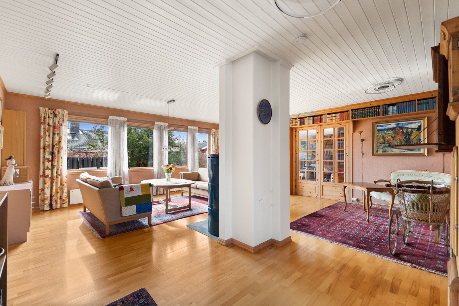 Lyst og romslig stue med peis, bibliotekshyller. Galleribilde