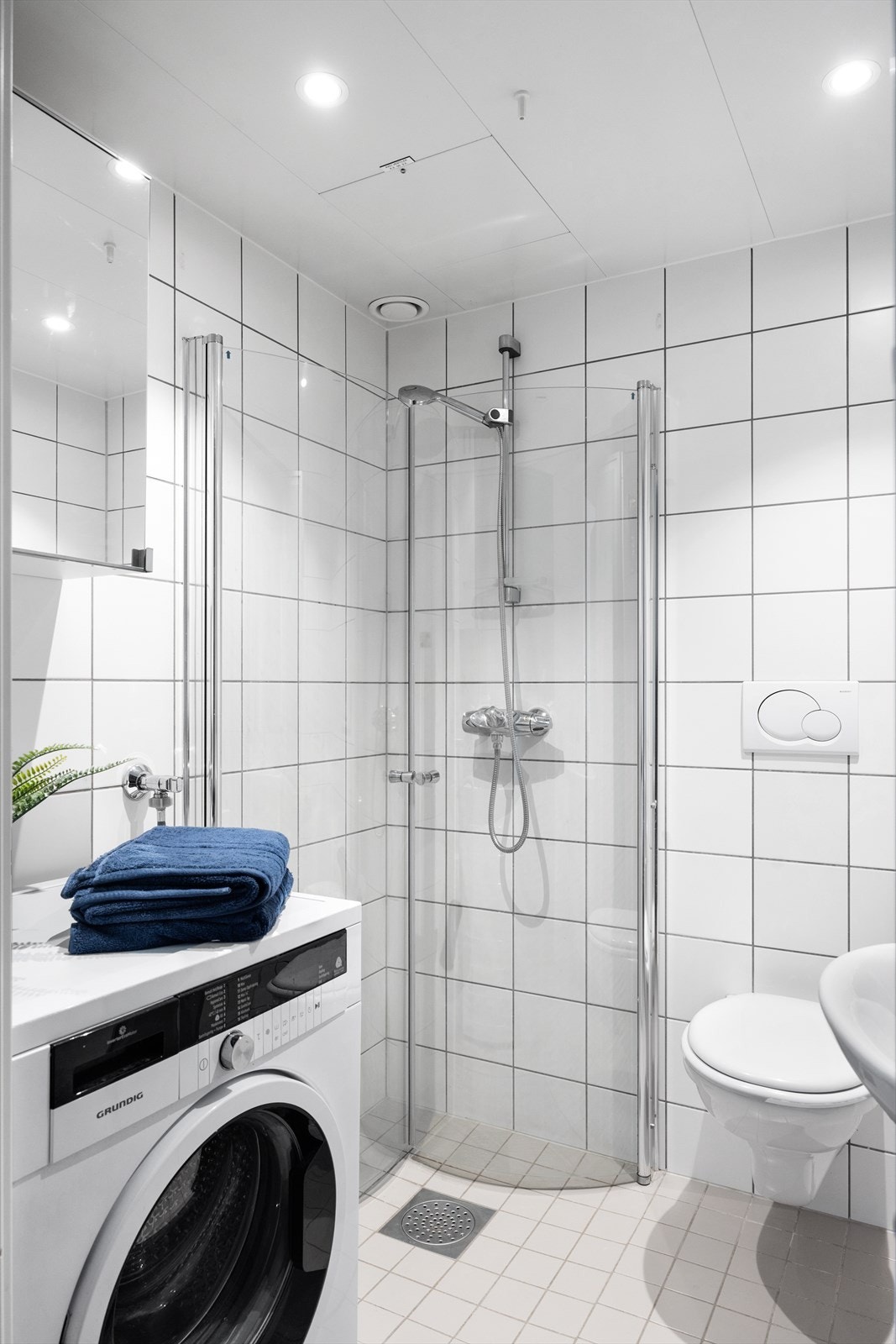 Badet er innredet med servantskap med glatte, folierte fronter, heldekkende servant, veggskap med speil fronter og veggmontert klosett. Dusjhjørnet har praktiske buede svingdører. Galleribilde