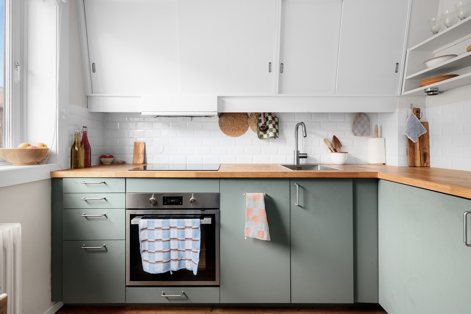 IKEA kjøkkeninnredning fra 2020 med malte/folierte fronter, benkeplate i tre med nedfelt kum i rustfritt stål, fliser på vegg over benk og ventilator med kullfilter. Integrert platetopp, stekeovn, oppvaskmaskin, kjøleskap og fryseskap. Galleribilde