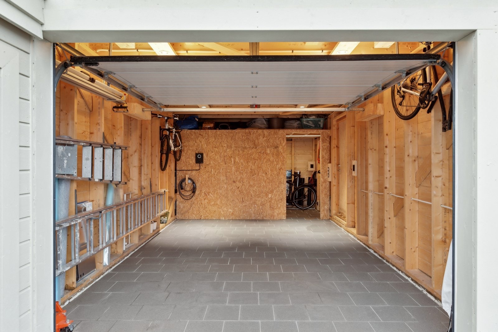 Garasjen er flislagt og med elbil lader. Praktisk bod i enden av garasjen. Oppstillingsplass på tomten. Galleribilde