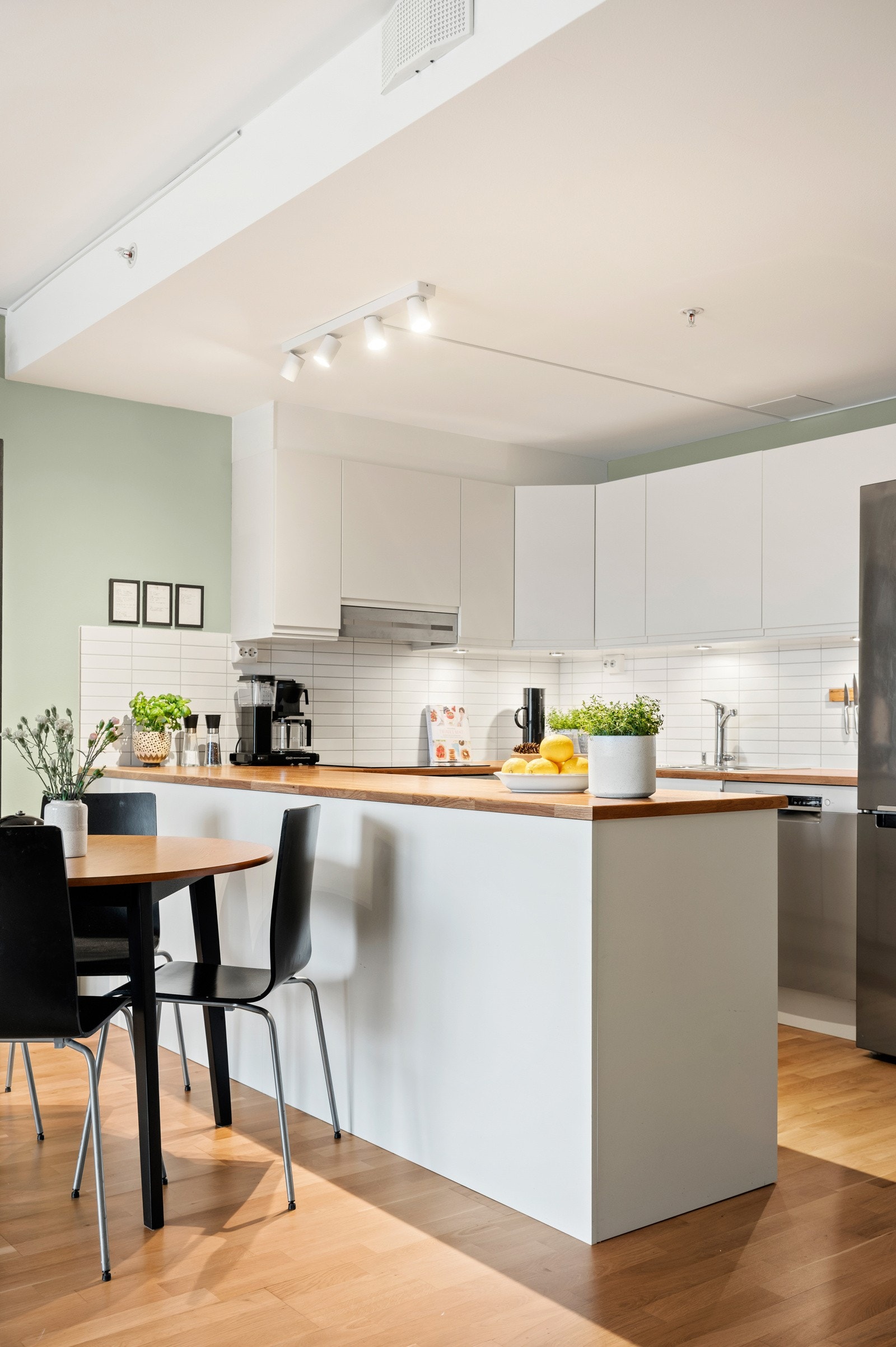 Leiligheten har et stilrent kjøkken med innredning bestående av hvite, glatte skapfronter og laminat benkeplater som gir et moderne og tidløst uttrykk Galleribilde