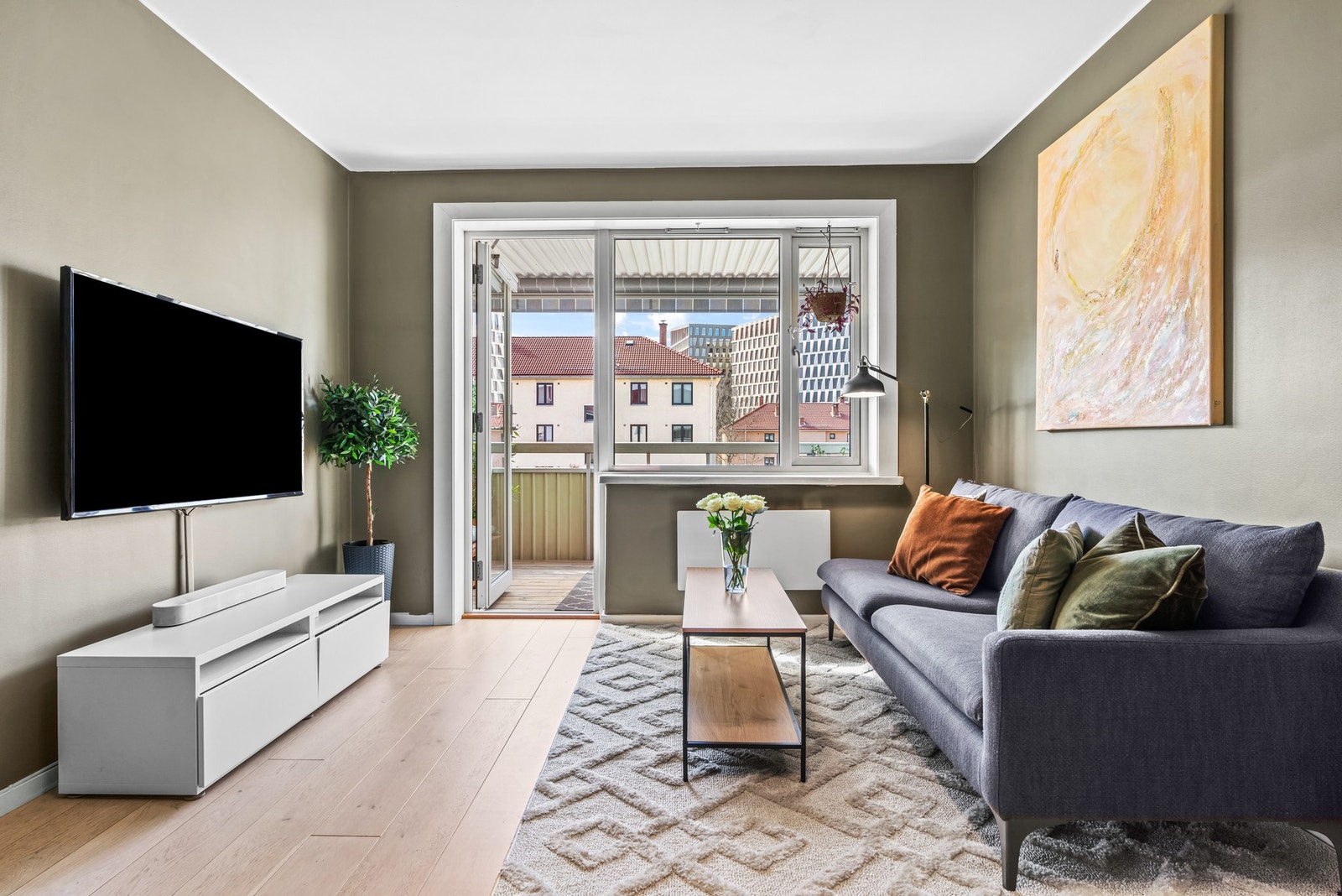 Stuen får godt med naturlig lysinnslipp fra store vindusflater mot vest. Både balkongdøren og vinduene ble skiftet i regi av brl. i 2018. Galleribilde