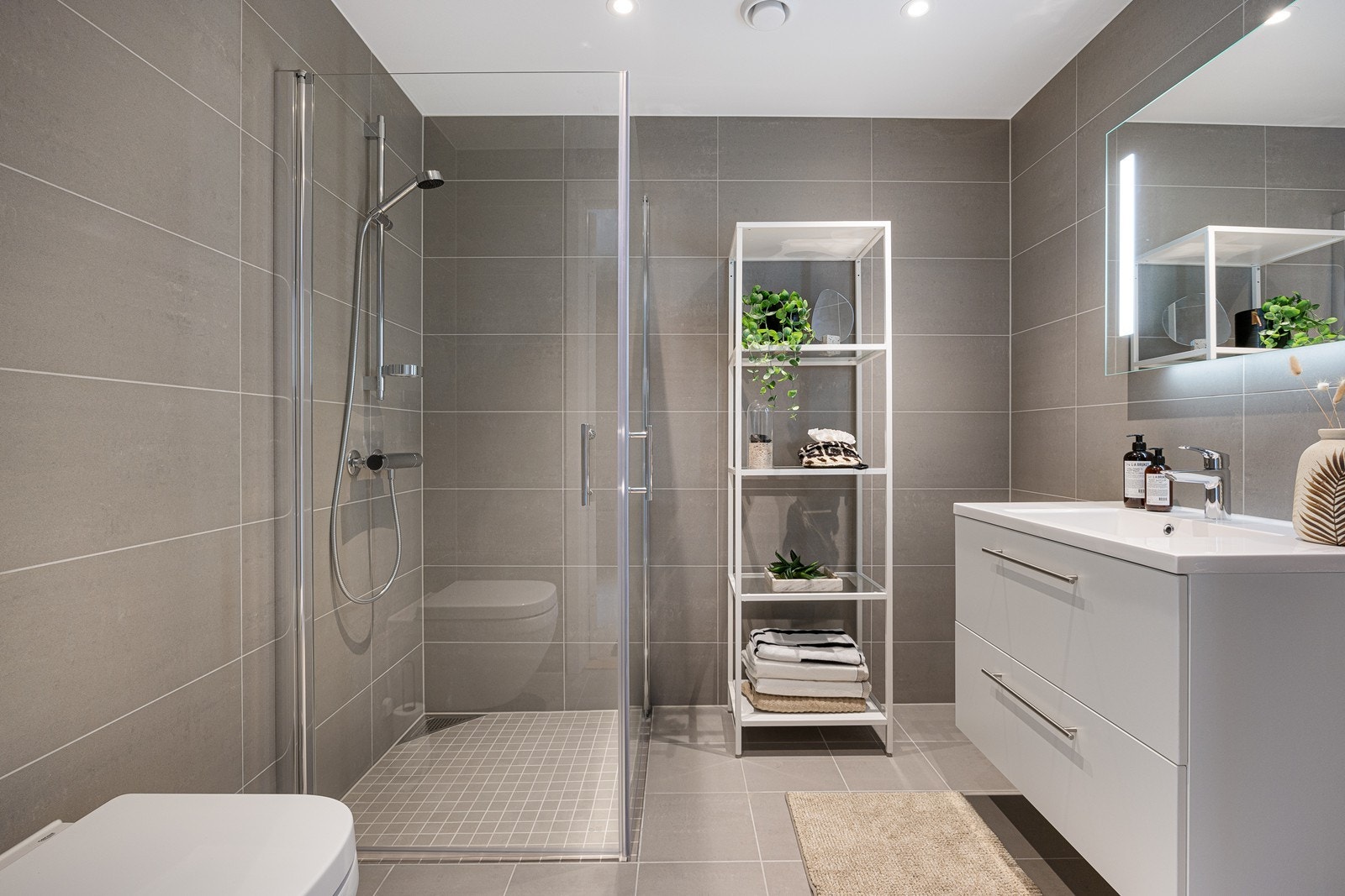 Badet er av god størrelse og har fliser i en lun gråfarge. Det er opplegg for vaskemaskin Galleribilde