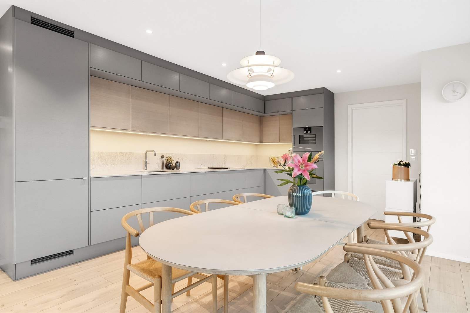 Integrerte hvitevarer kjøleskap med frysedel, komfyrer i høyskap, nedsenket induksjonsplatetopp i benkeplate med innebygget ventilator. Galleribilde