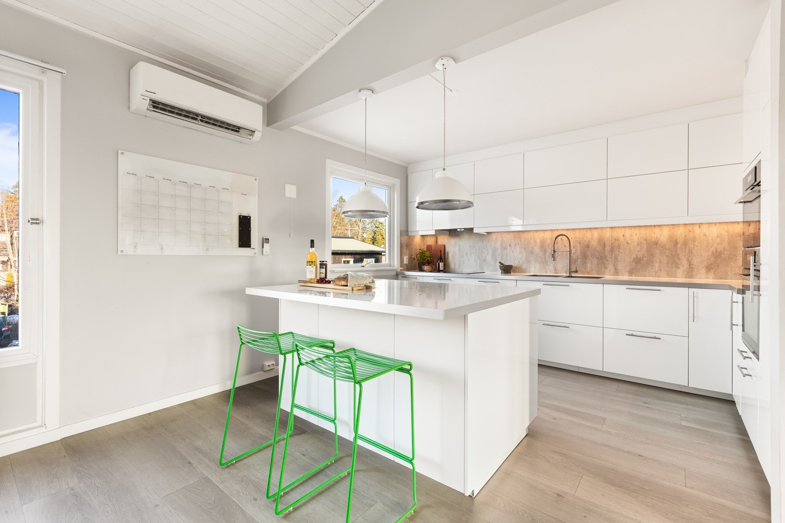 Et herlig kjøkkenrom med stor kjøkkenøy som skiller kjøkken fra spisestue. Luft-til luft-varmepumpe gir god varmeeffekt til etasjen. Galleribilde