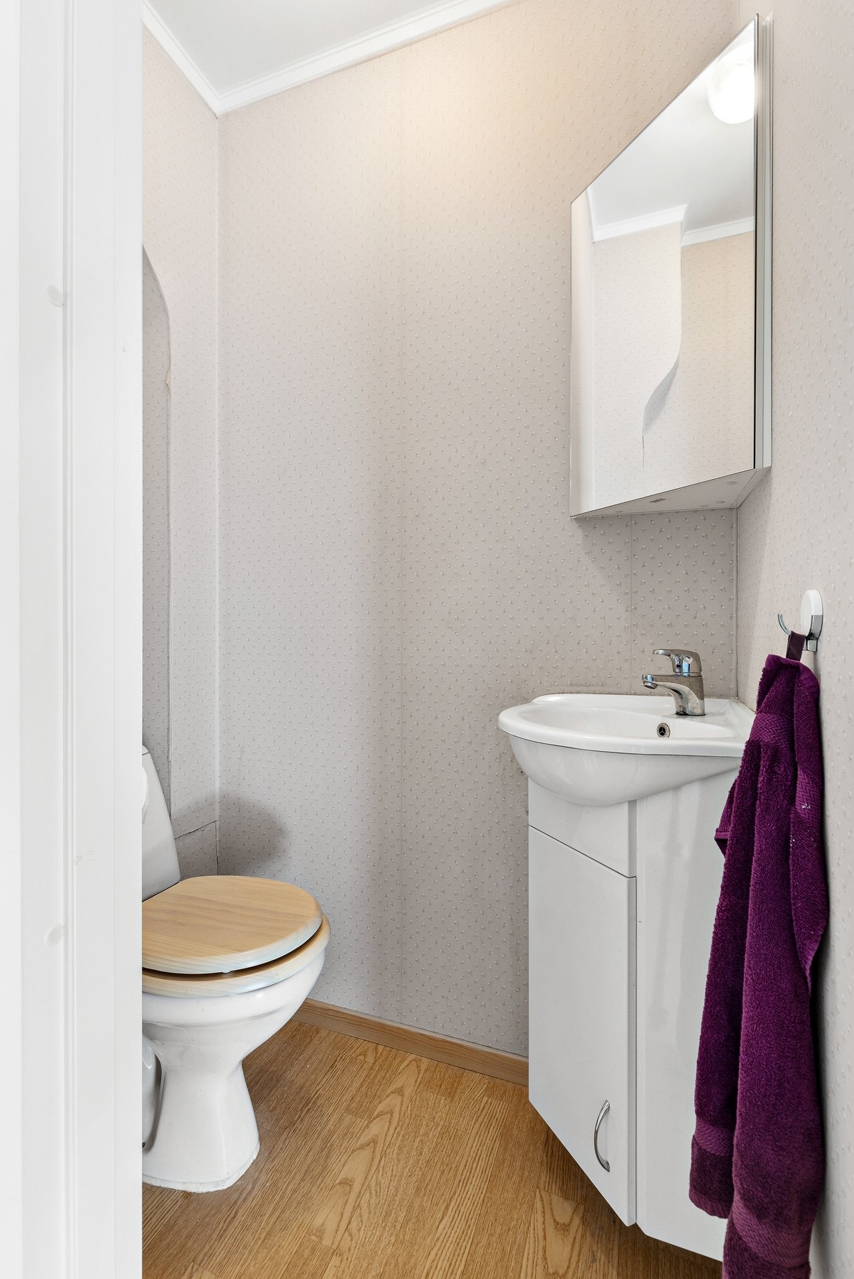 Separat toalettrom med gulvstående toalett, innredning med ovenpåliggende servant og vegghengt speilskap Galleribilde