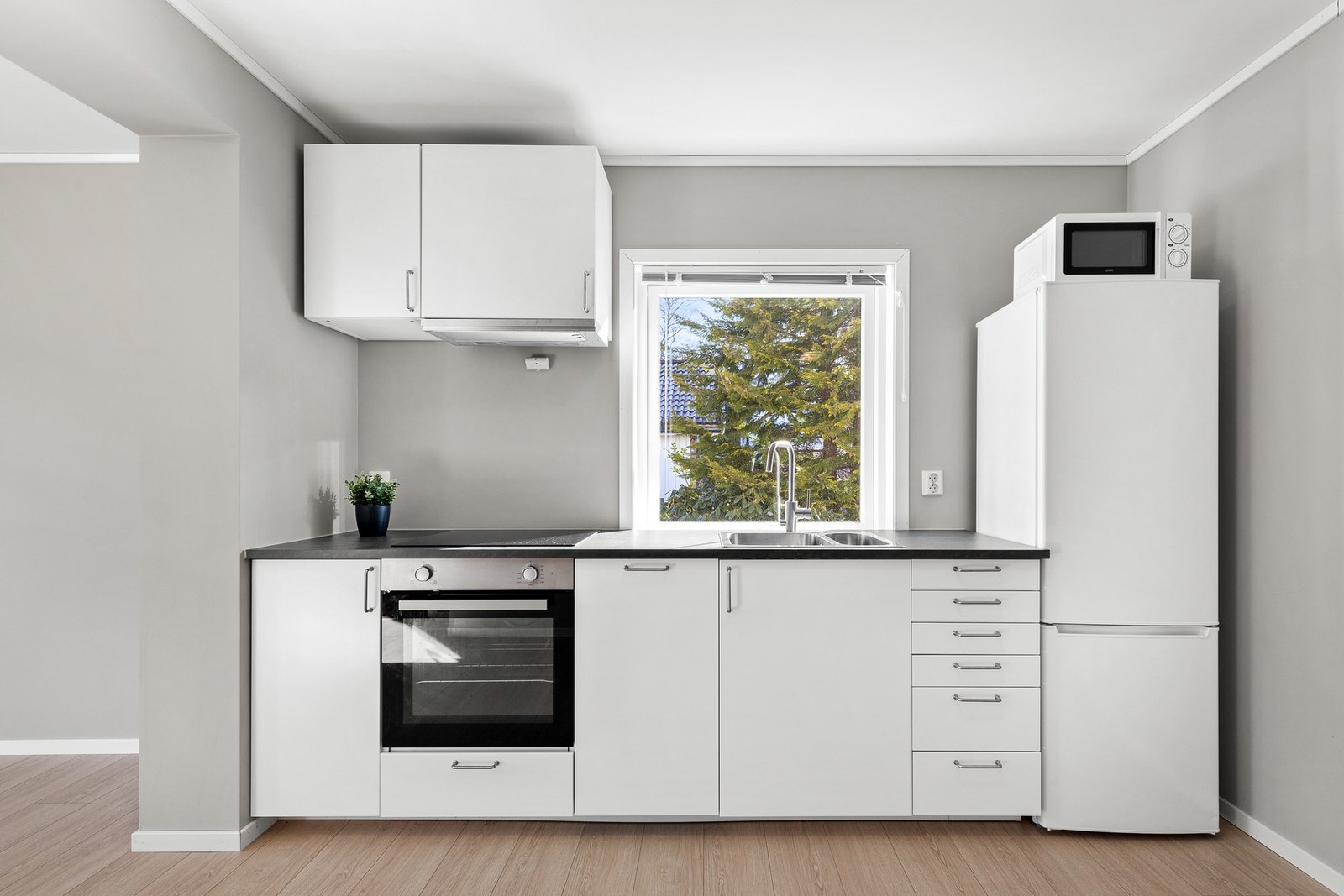 Kjøkkenet har integrert komfyr, nedfelt platetopp, komfyrvakt og ventilator i overskap, samt integrert oppvaskmaskin under benkeplate Galleribilde