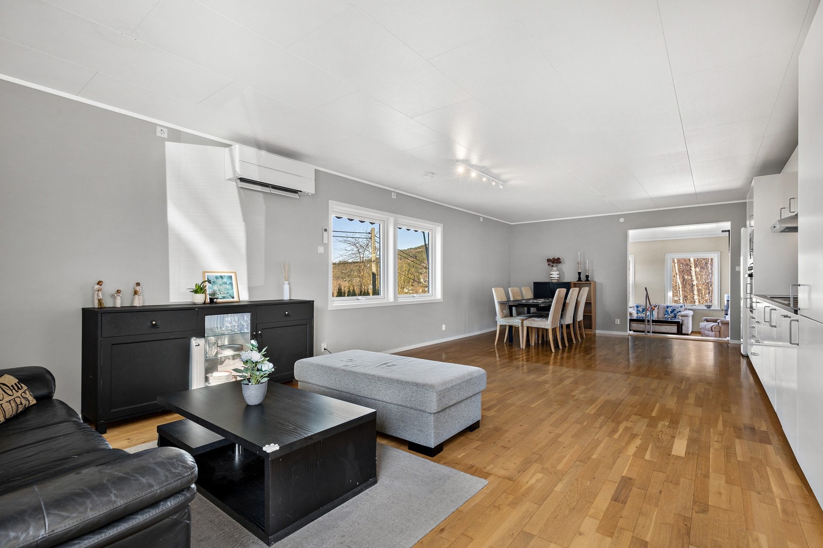 Lys og romslig stue med trestavs parkett på gulv, slette vegger og takplater i himling Galleribilde