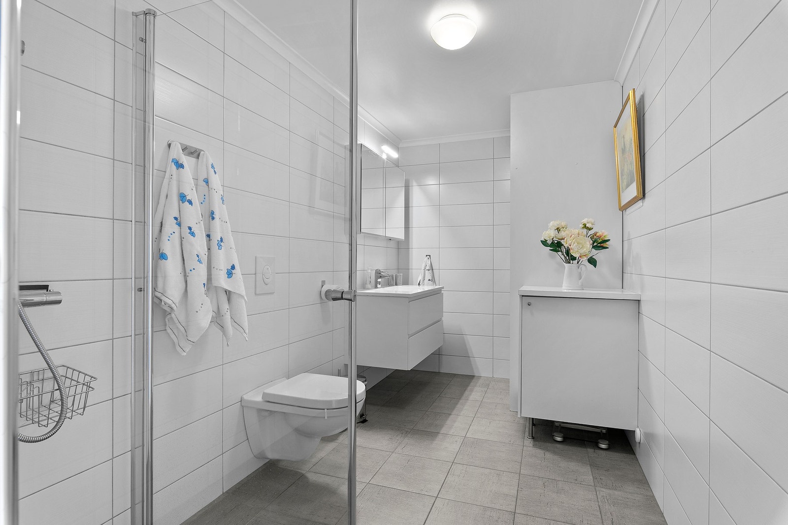 Stort og stilrent bad utstyrt med opplegg for vaskemaskin, vegghengt toalett, dusjhjørne med hånddusj og regndusj, samt speilskap med overlys. Galleribilde