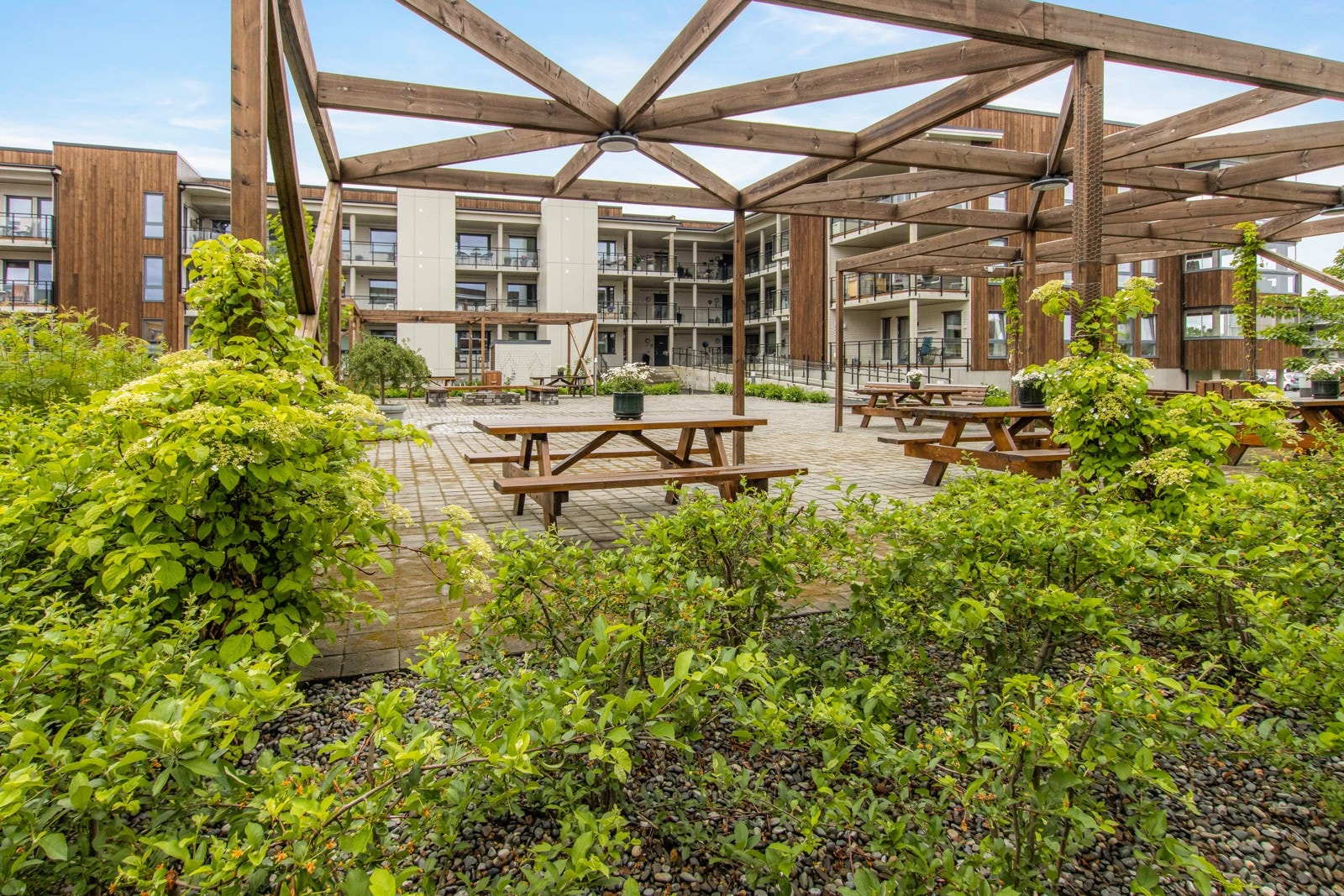 Belegningsstein, sittebenker, diverse beplantning, vannfontene, felles grillplass, belysning og "paviljonger". Galleribilde