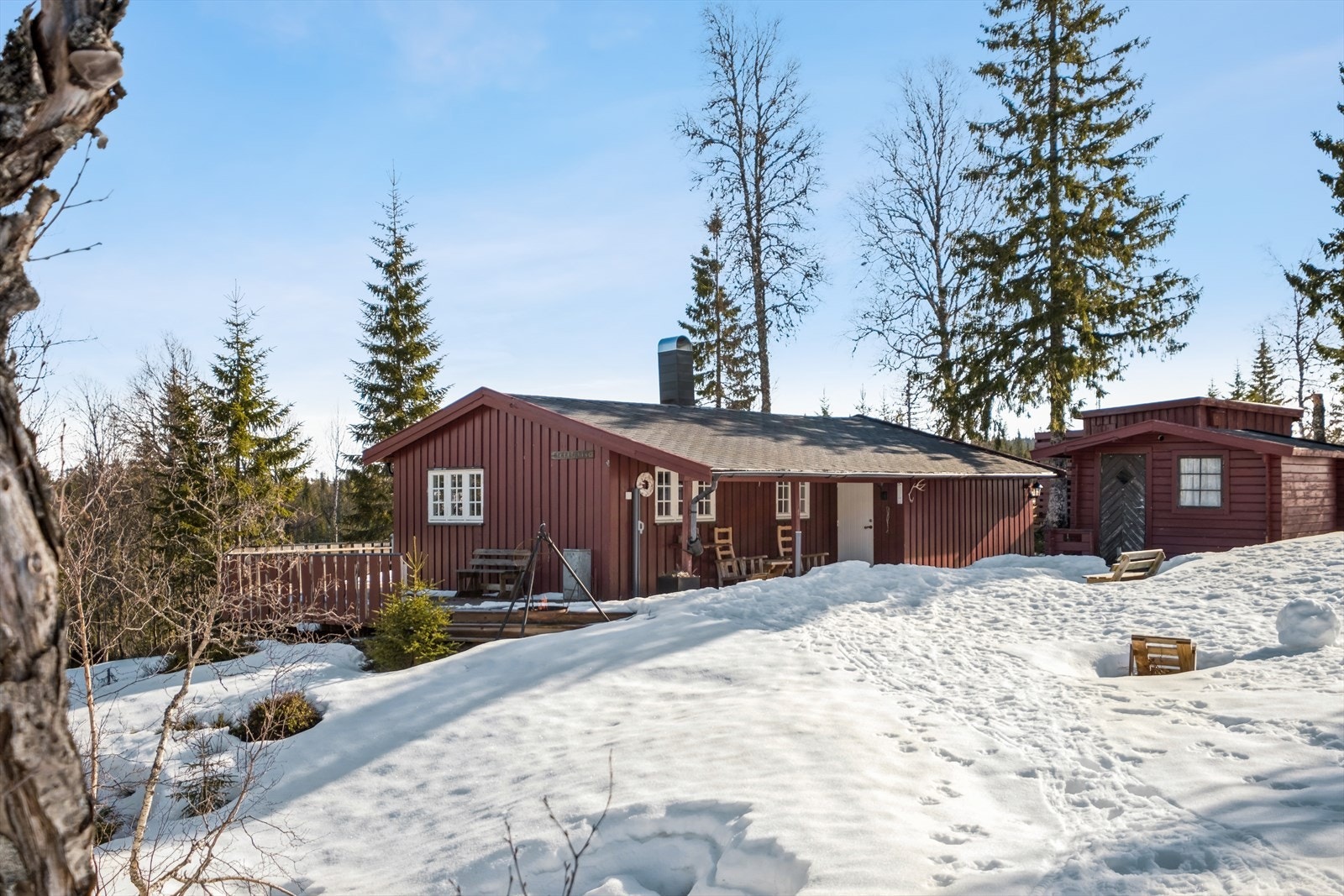 Lite innsyn inn mot hytta og stort flattparti utenfor døra og myra over hytta. Galleribilde