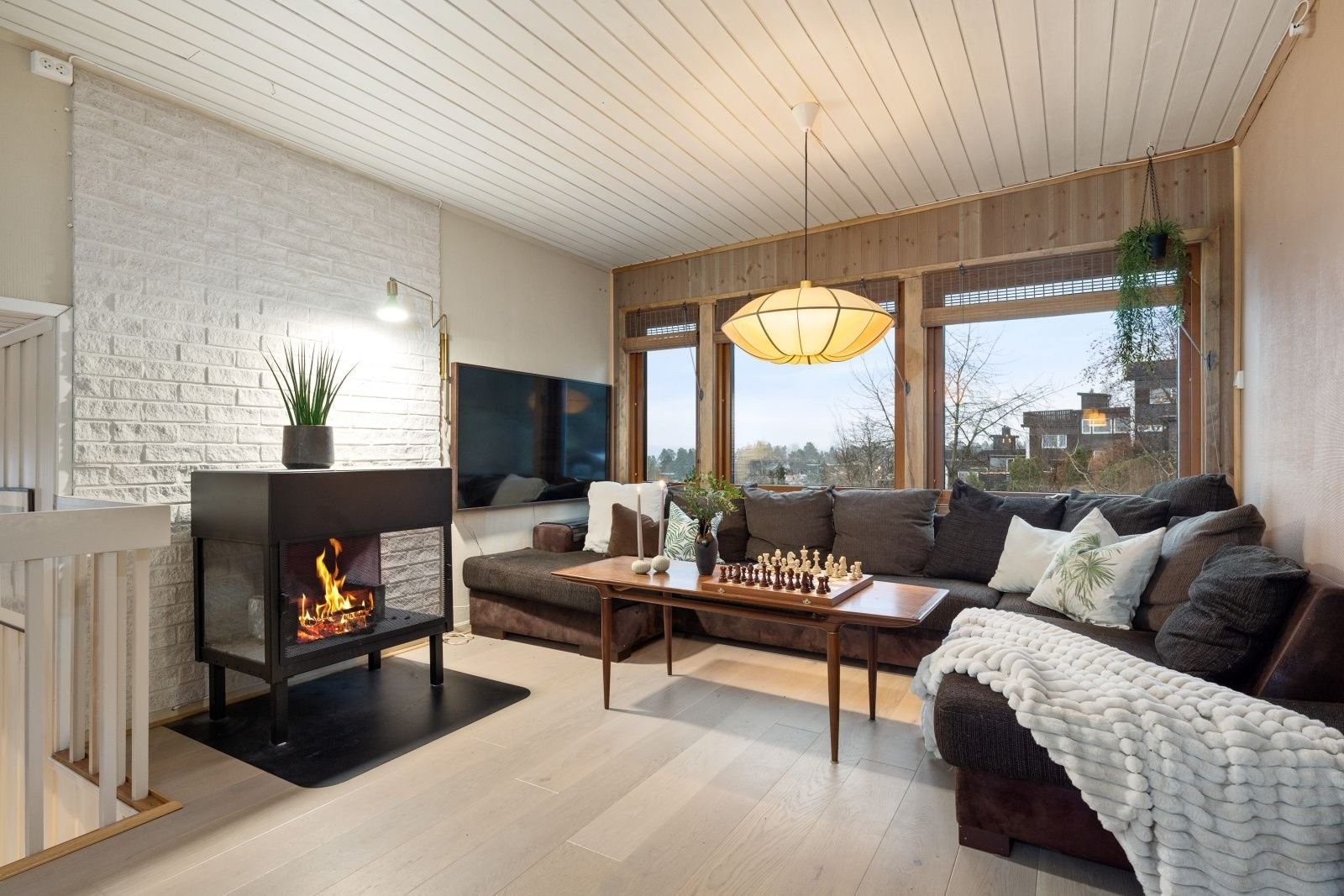 Store vinduer med utsikt mot hagen og sjøen. På våren kan man nyte synet av kirsebærtreet i full blomst. Peisen er mest for kosens skyld, da boligen blir varm nok med varmepumpe. Det er også en vedovn i første etasje. Galleribilde