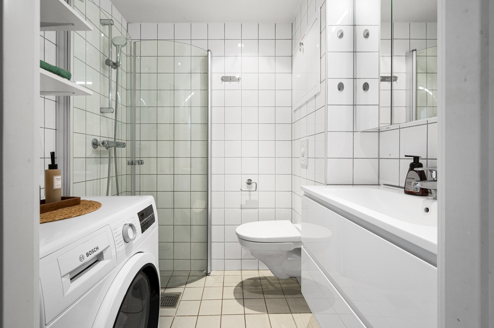 Leilighetens baderom har dusjhjørne med innfellbare dører og opplegg til vaskemaskin Galleribilde