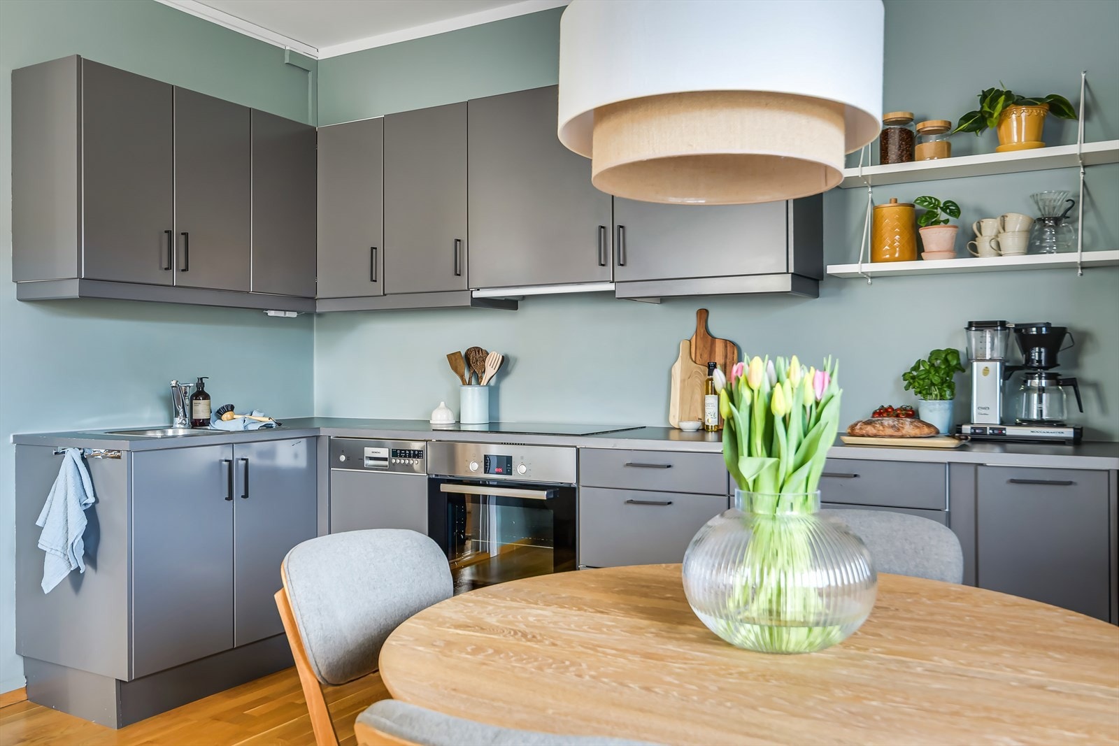 En mørk kjøkkeninnredning med glatte flater, benkeplate av laminat og med nedfelt oppvaskkum. Galleribilde