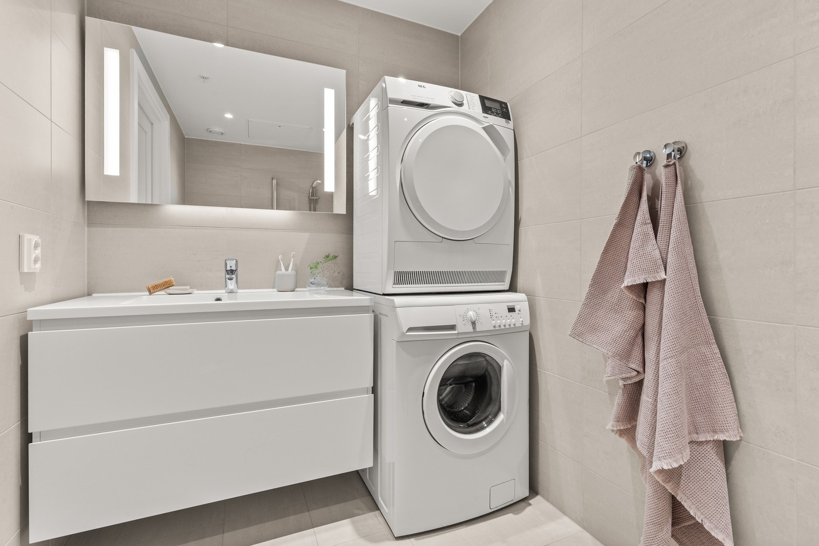 Badet er utstyrt med dusj med innfellbare glassvegger, servantseksjon med skuffer og heldekkende komposittvask, speil med lys, vegghengt wc og opplegg for vaskemaskin/tørketrommel. Galleribilde