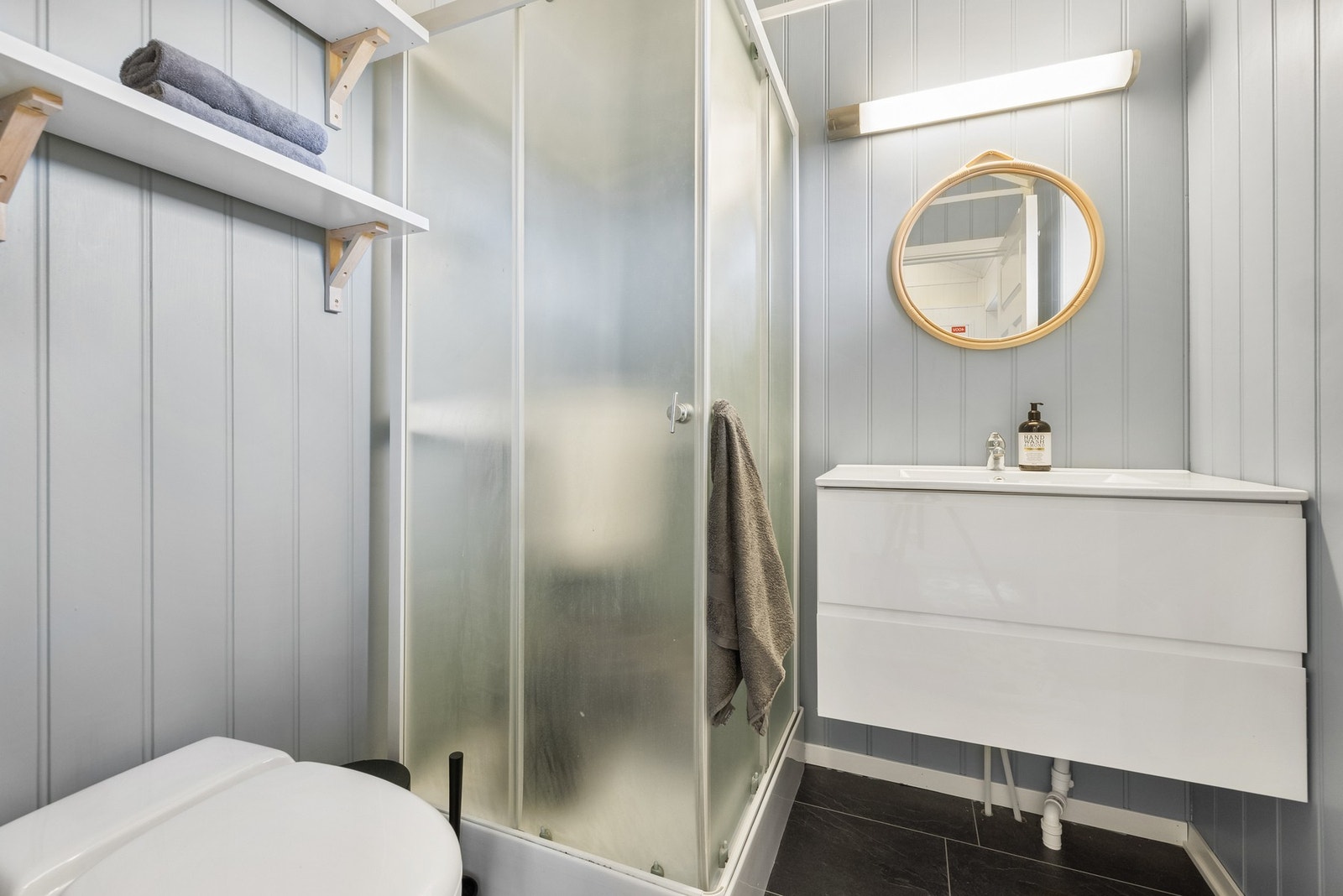 Toalettrom med snurredass og dusjkabinett med vanntank som er tilkoblet en elektrisk pumpe Galleribilde