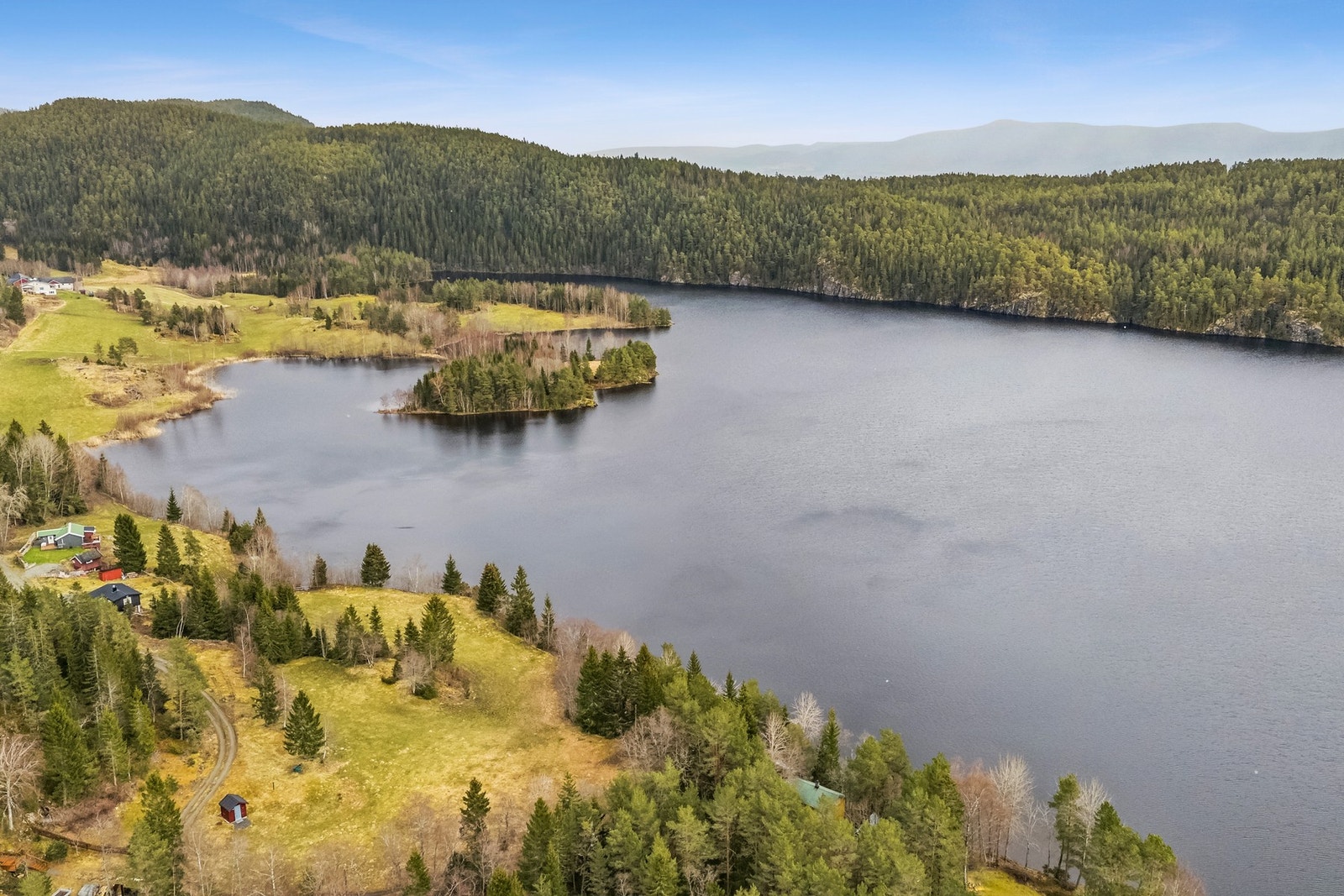 Eiendommen har en sjeldent vakker beliggenhet - høyt og fritt på en liten høyde ved Hovdalsvatnet, med panoramautsikt over vannspeilet og kun ca. 35 meter til vannkanten. Galleribilde