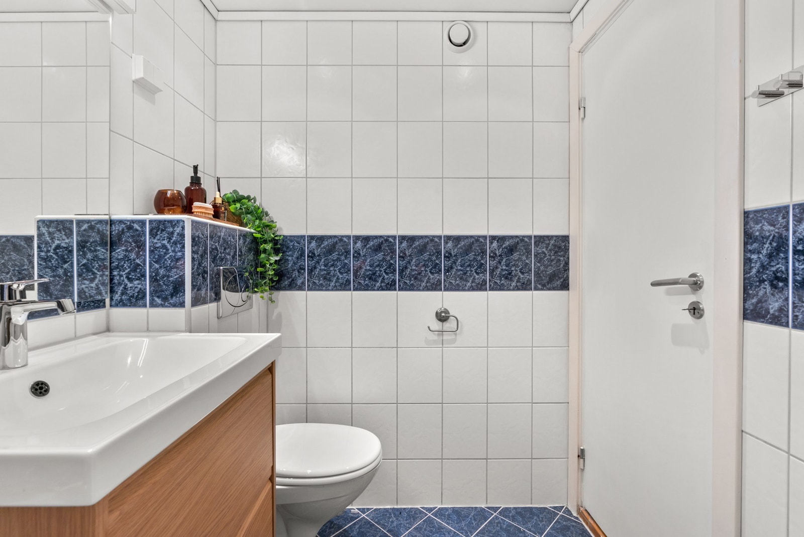 Baderomsinnredningen har finerte fronter og består av en heldekkende servant på en skuffeseksjon og et speil med belysning, samt et vegghengt toalett. Galleribilde