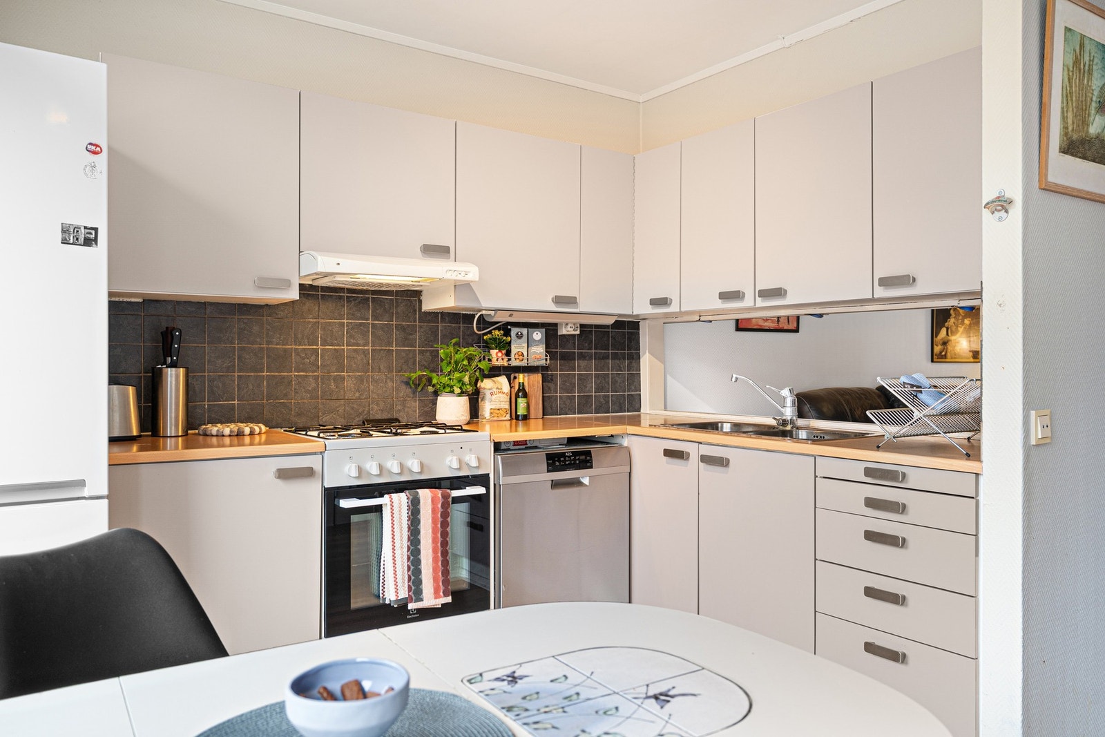 Kjøkkeninnredning med over- og underskap, plane møbelplater i fronter
og laminerte benkeplater. Galleribilde