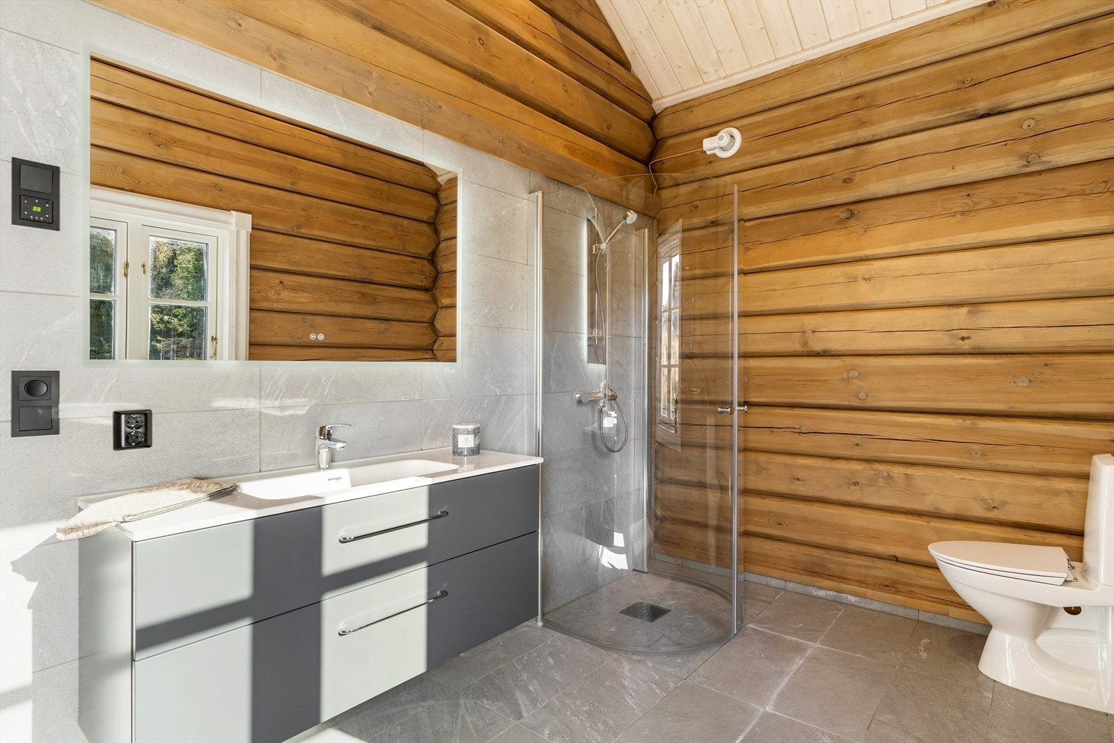 Badet er innredet med servantskap med skuffer, dusjhjørne og toalett. Galleribilde