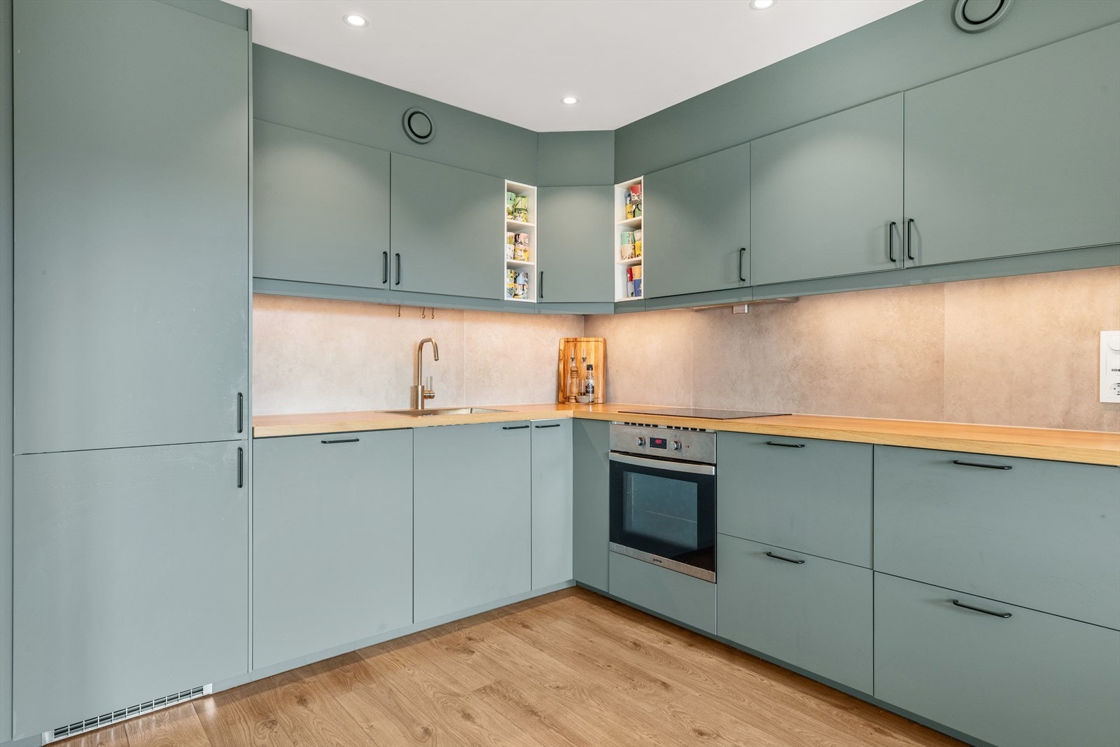 Kjøkkeninnredning med nye, slette fronter i 2022 og heltre benkeplate med nedfelt oppvaskkum. Glassplate på vegg over kokesone gjør det også enkelt og rengjøre. Galleribilde