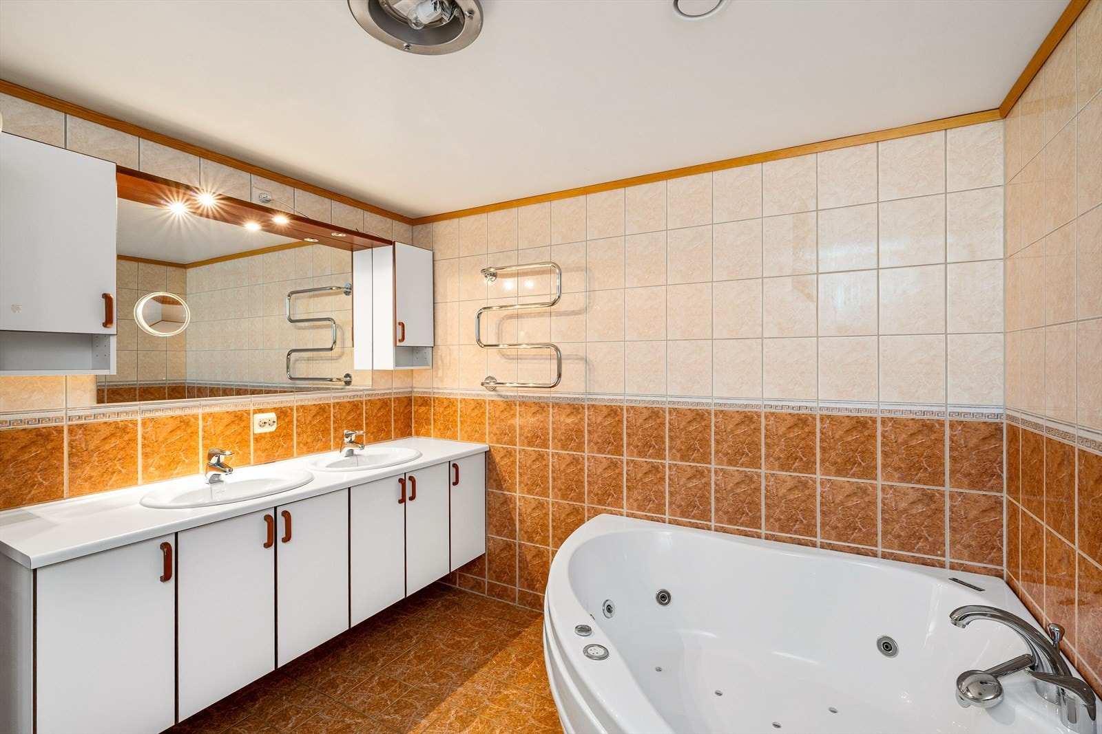 Badet er innredet med dobbel vask i seksjon, boblebadekar, speil med belysning, toalett og dusjhjørne. Galleribilde