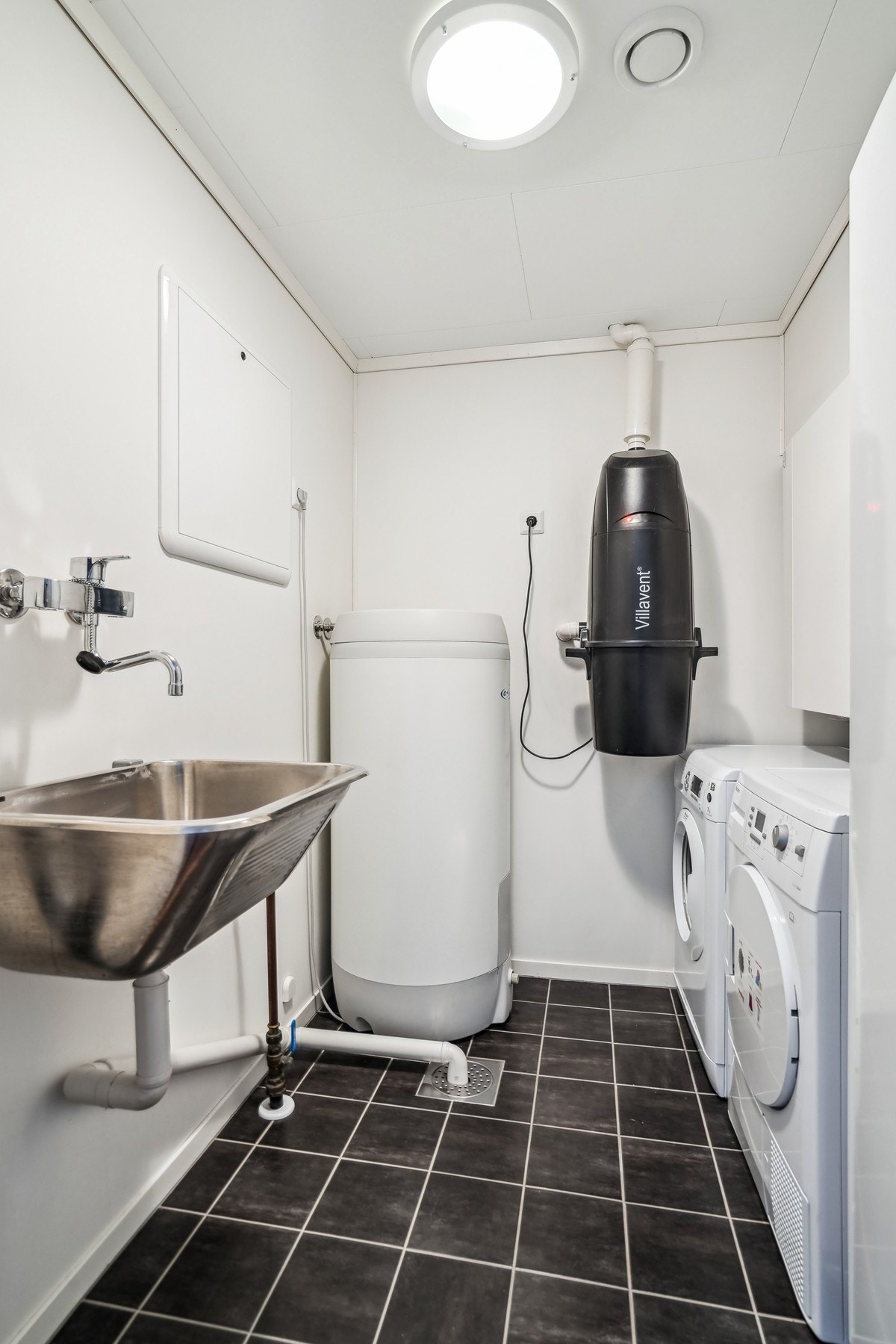 Boligen har separat vaskerom med flislagte gulv. Her er utslagsvask, tekniske installasjoner og avsatt plass til vaskesøylen. Sentralstøvsuger er også montert her. Galleribilde