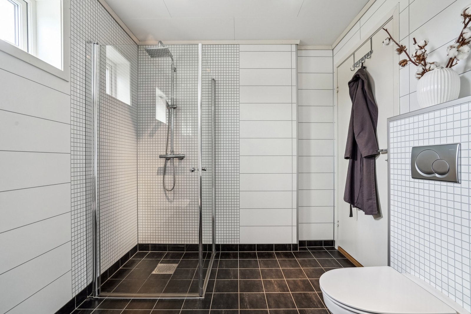 Videre er badet utstyrt med vegghengt toalett og dusjhjørne med innsvingbare dusjdører. Galleribilde