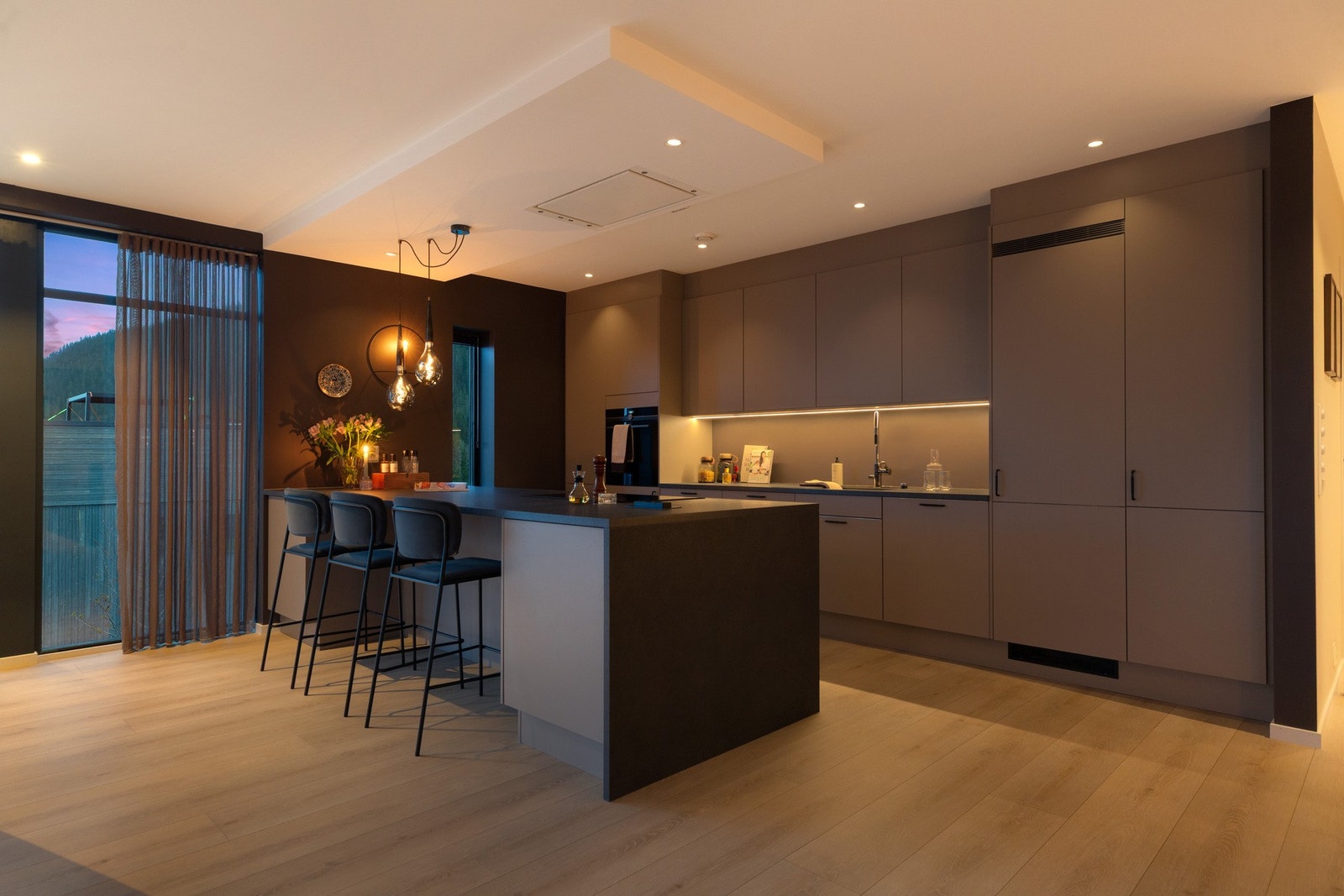 Råstilig kjøkken fra Sigdal med en stor kjøkkenøy som gir en naturlig adskillelse mellom kjøkken og stue Galleribilde