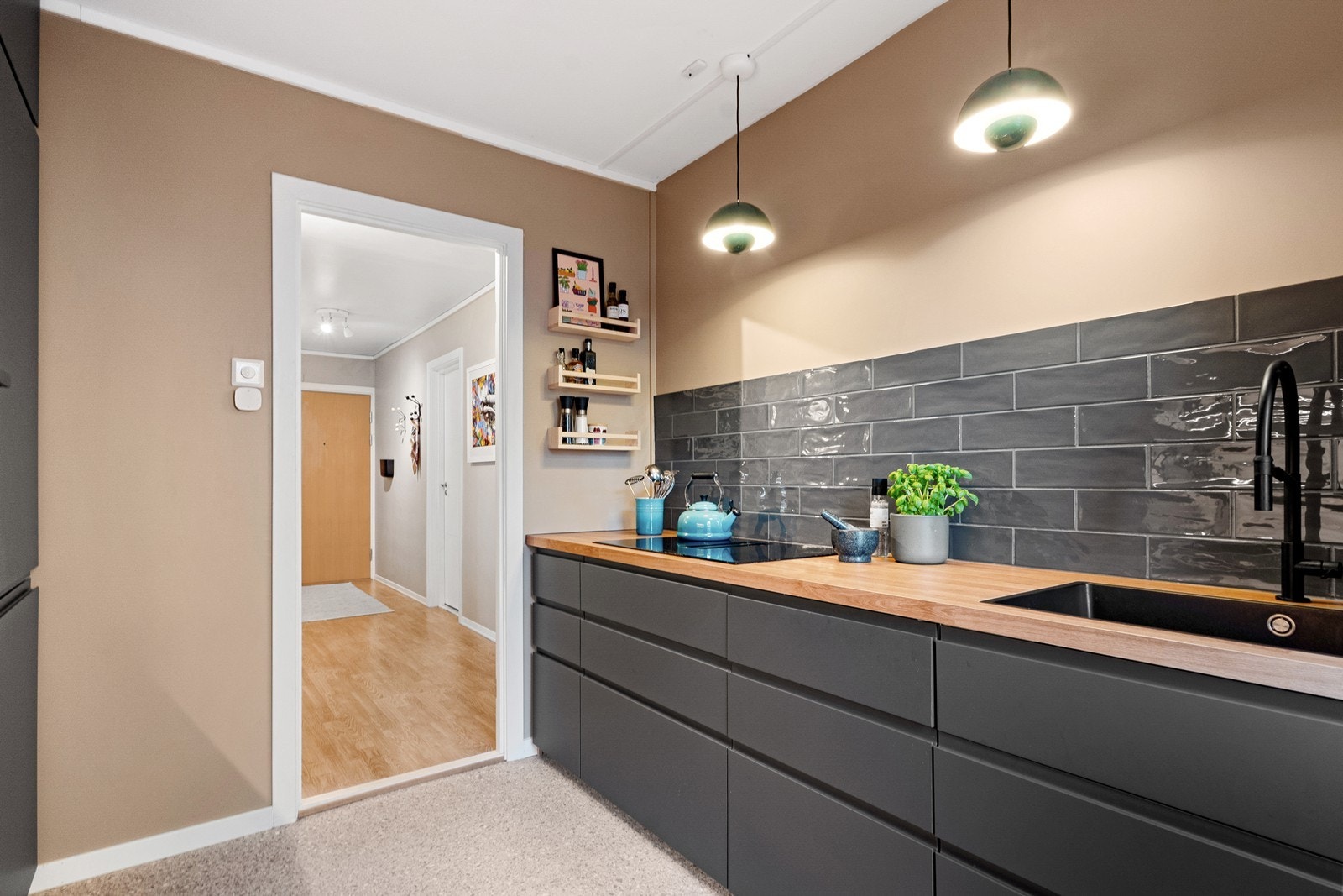 De mørke, slette frontene gir et moderne preg i kombinasjon med benkeplate i treimitasjon og stilige, blanke fliser over benk på en side. Galleribilde