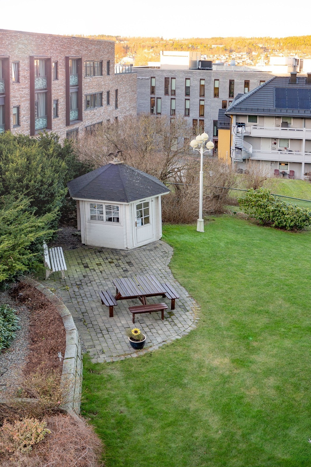 Borettslagets bakgård er opparbeidet med bla.a. gressplen, belegningsstein, utelys, bed, busker og et felles lysthus. Galleribilde
