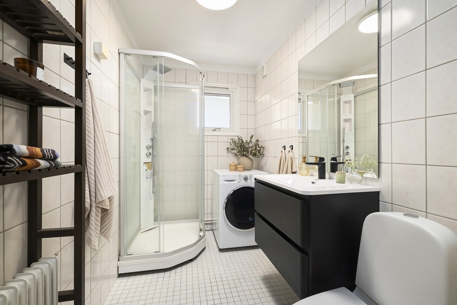 Badet har dusjkabinett, opplegg for vaskemaskin og servantskap med skuffer Galleribilde