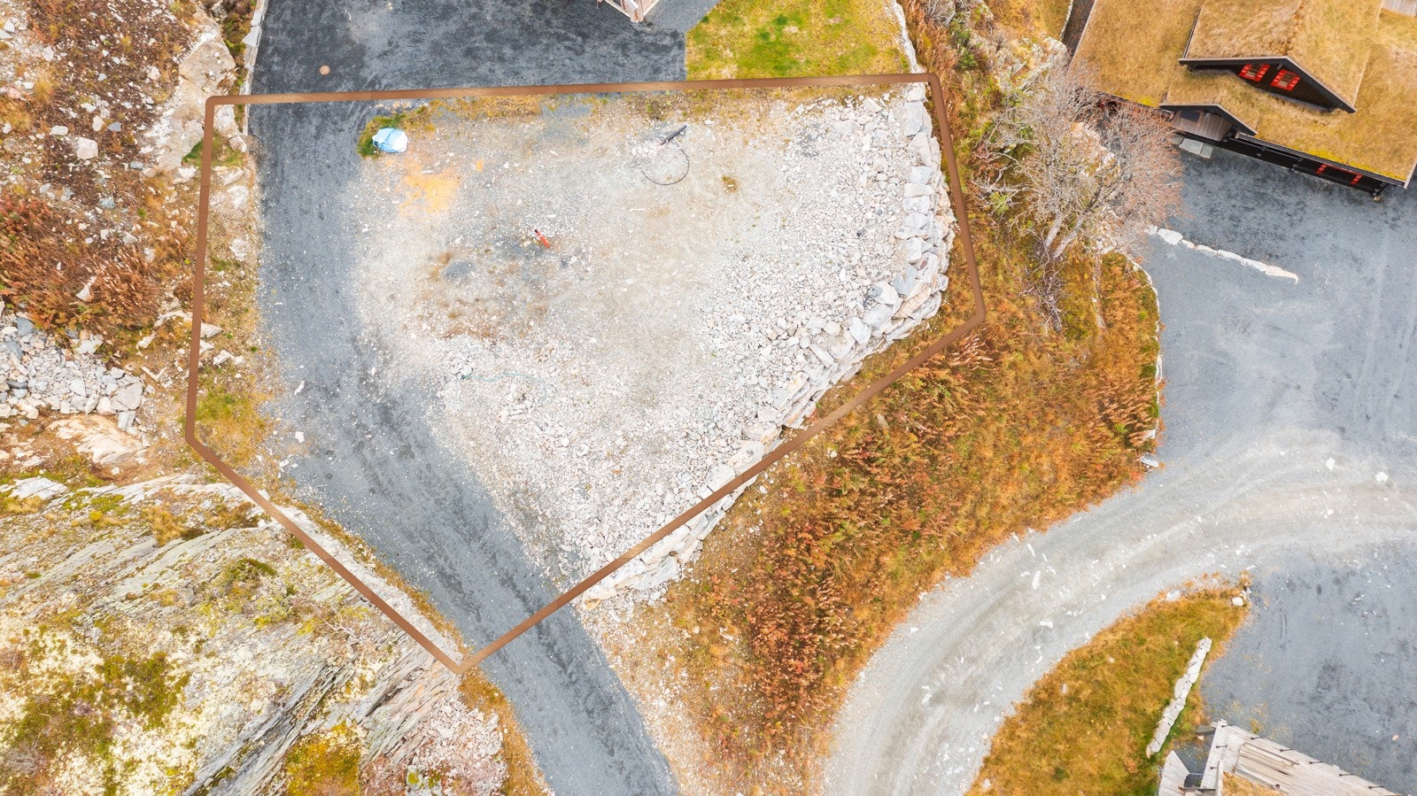 Tomten er sprengt ut i fjell og er ferdig opparbeidet - klart for bygging. Flott natursteinsmur rundt fronten av tomten Galleribilde