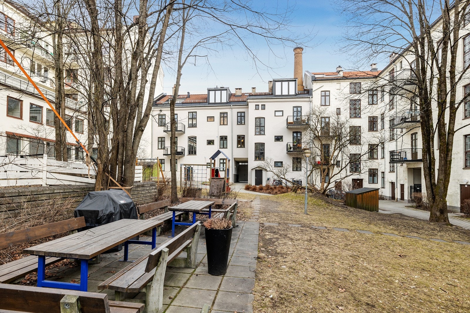 Bakgården er opparbeidet med store grønne plenarealer, diverse beplantning og asfalterte områder. Galleribilde